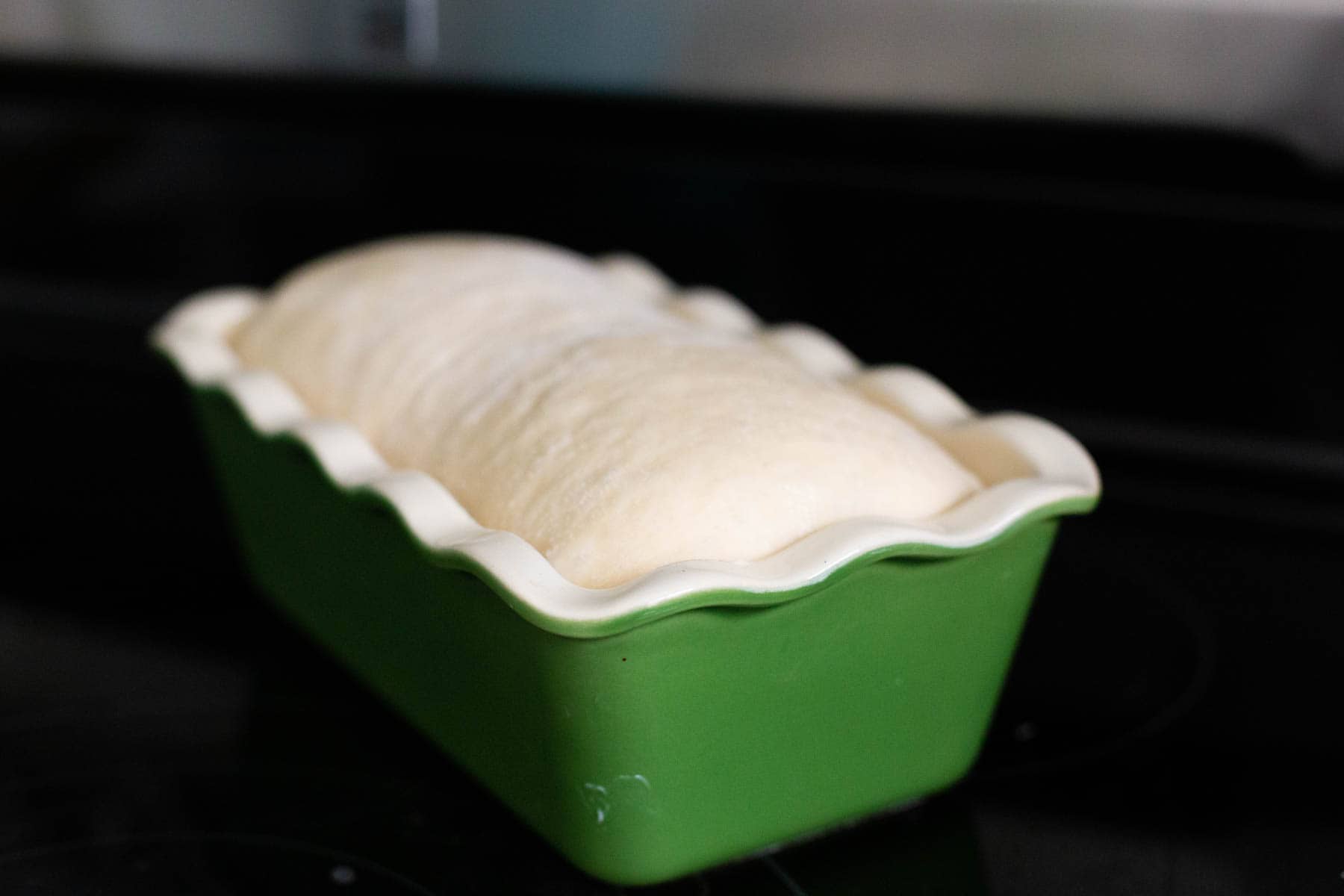 The cinnamon swirl bread has risen just above the edges of the baking pan.