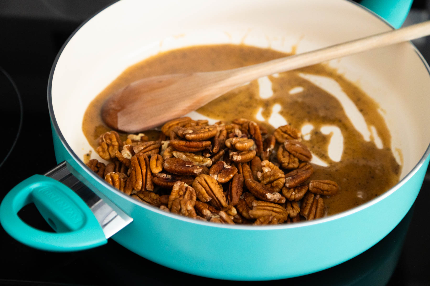 The pecans are in a large skillet with the melted glaze.