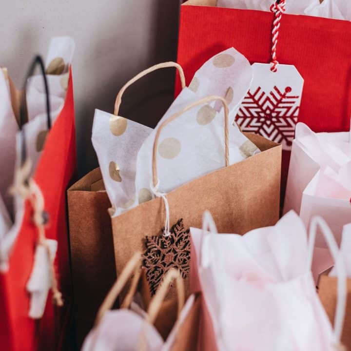 A pile of shopping bags with Christmas patterned tissue paper.