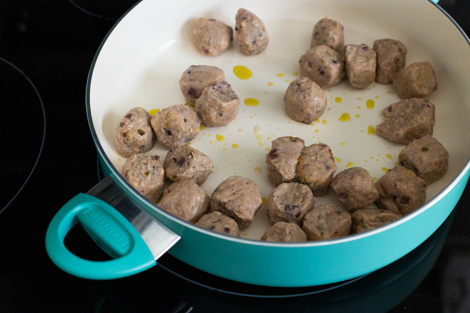 The prepared meatballs are browning in a large skillet with a little olive oil.