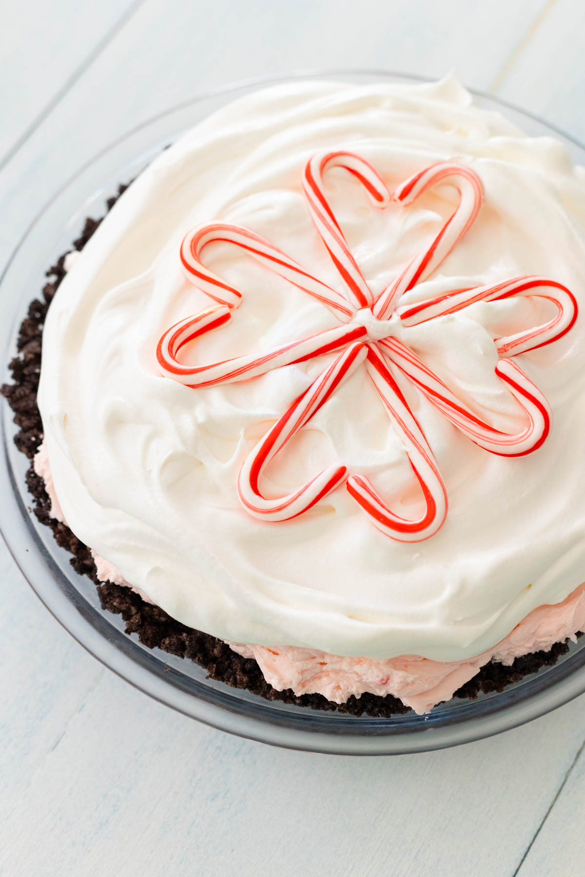 The Christmas dessert has been frosted with Cool Whip and 8 mini candy canes have been arranged to form a heart-shaped snowflake on top.