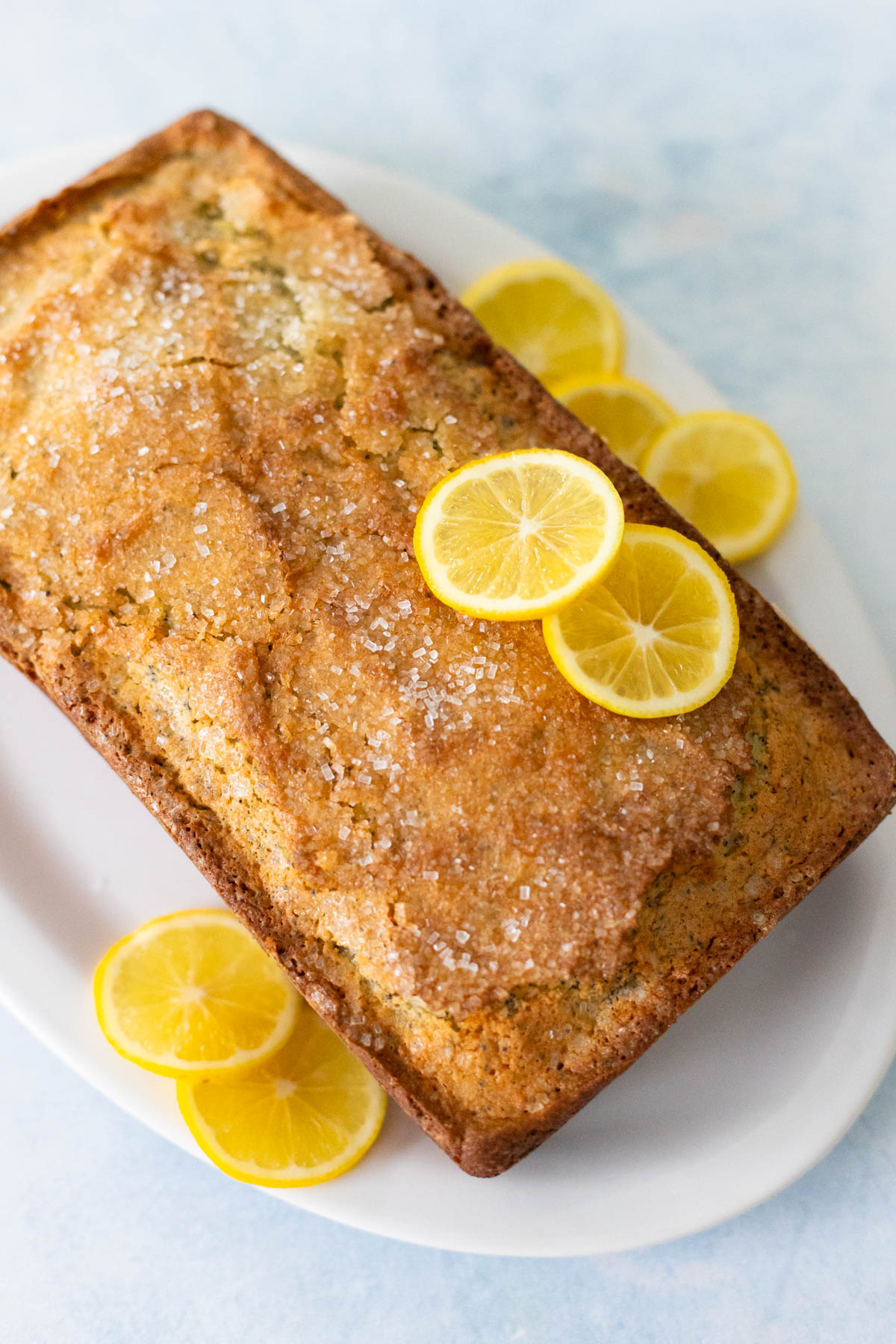 The lemon poppy seed bread is fresh from the oven and a pretty golden brown color all around. Sliced lemons have been added for garnish.