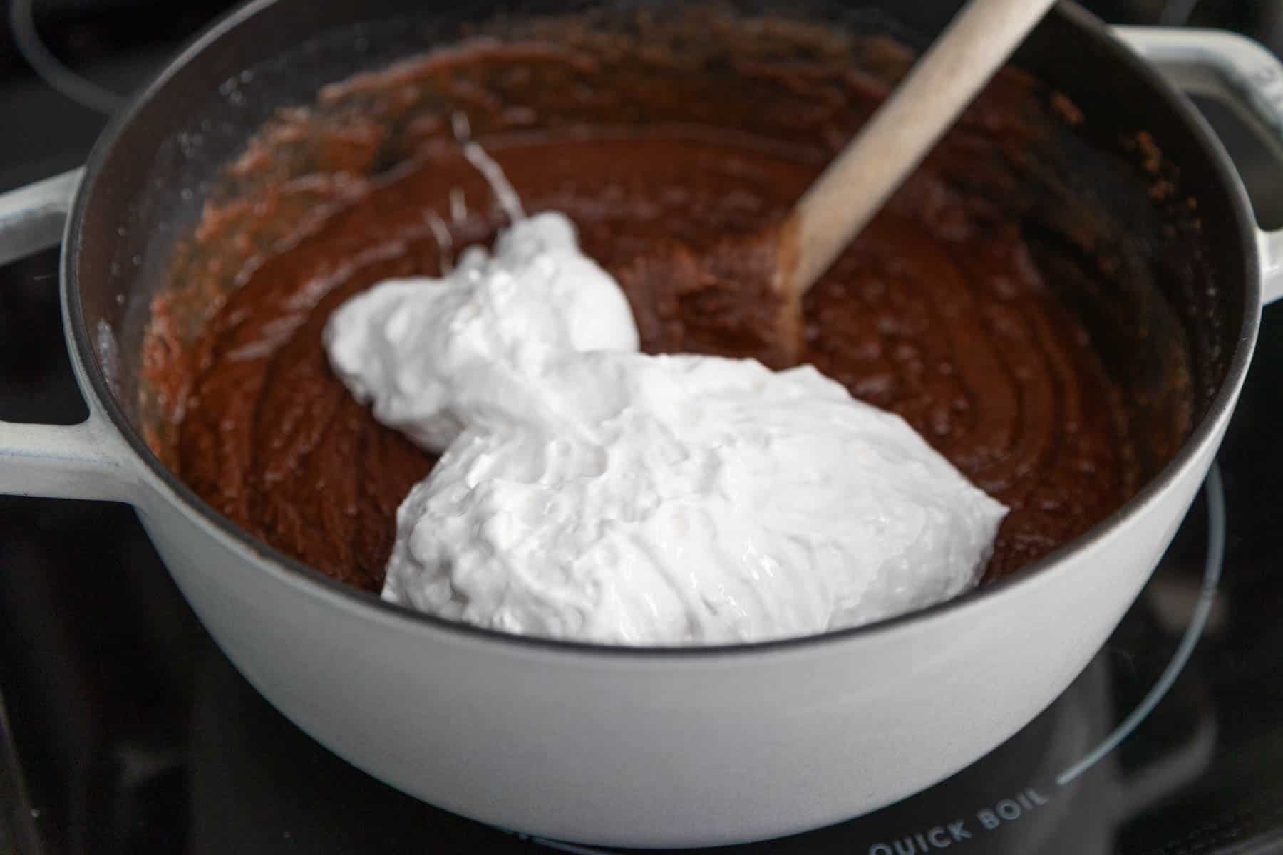 The marshmallow creme is being stirred into the fudge.