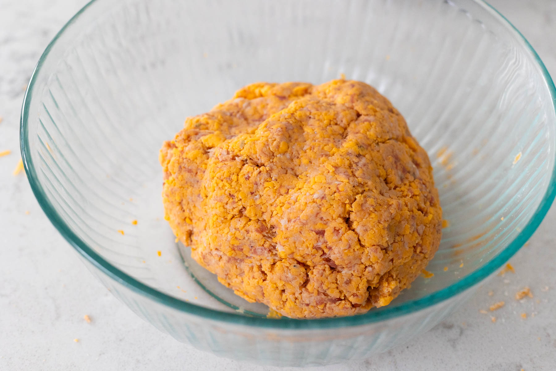 The sausage, cheese, and Bisquick mix have been kneaded together and formed a large ball.