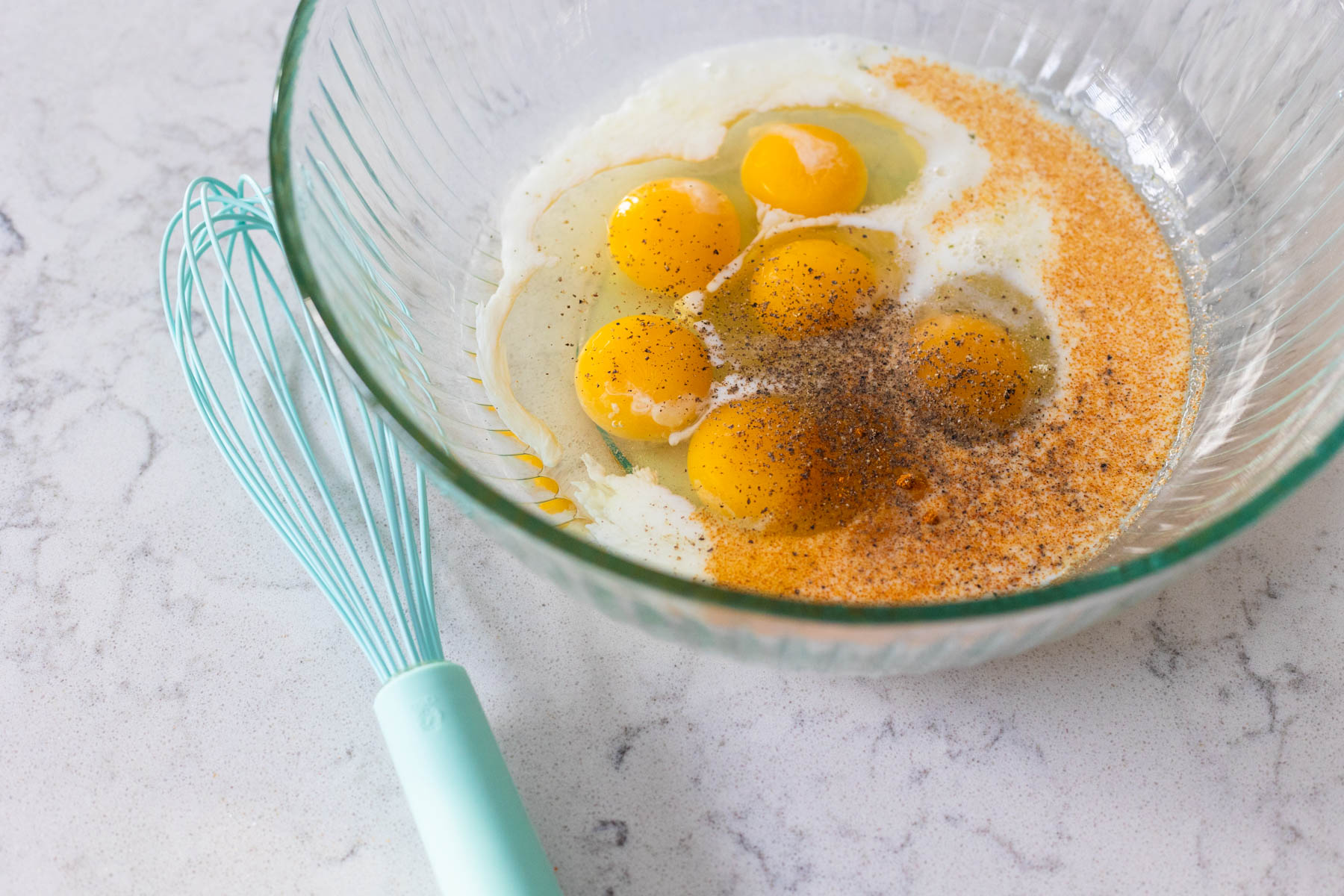 The eggs have been added to a mixing bowl with milk and seasonings.