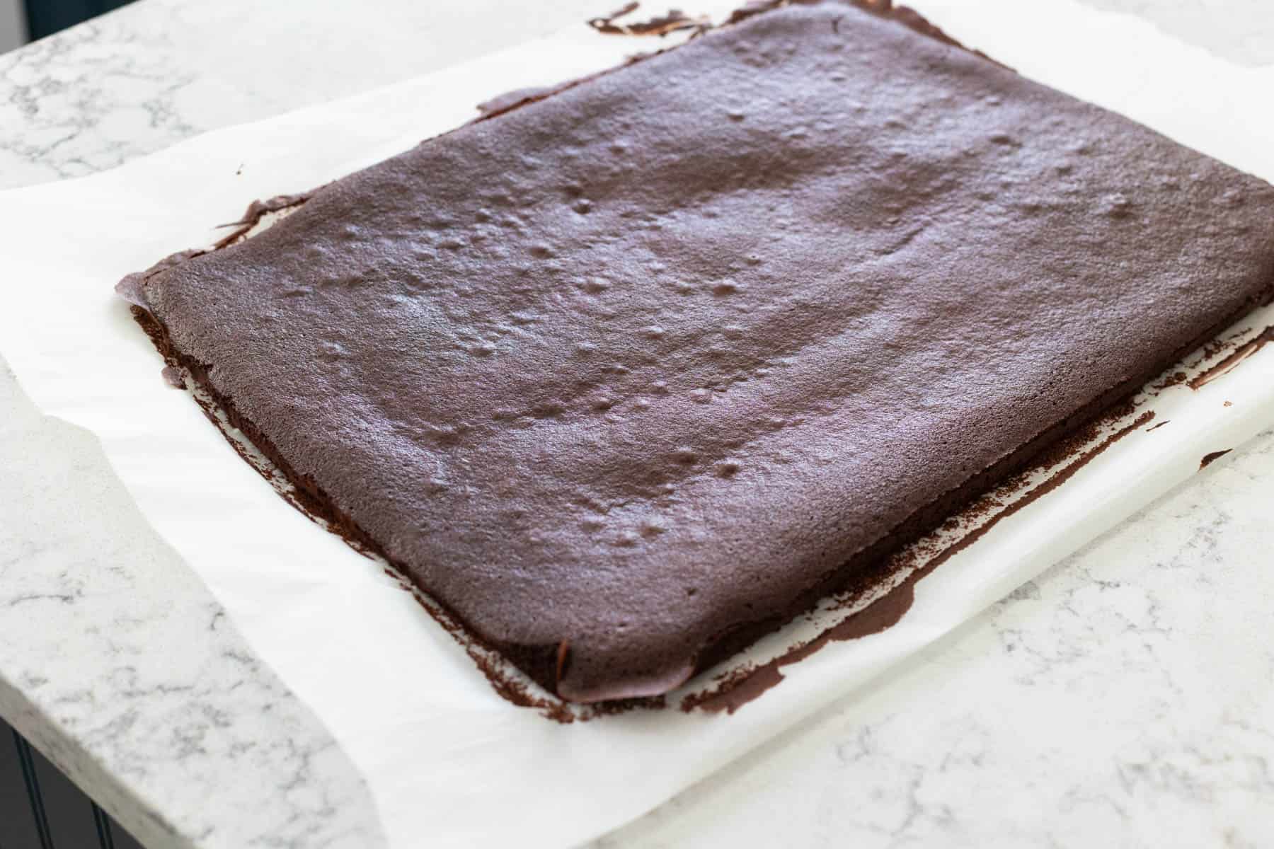 The cake is out of the oven and cooling slightly on the parchment paper.