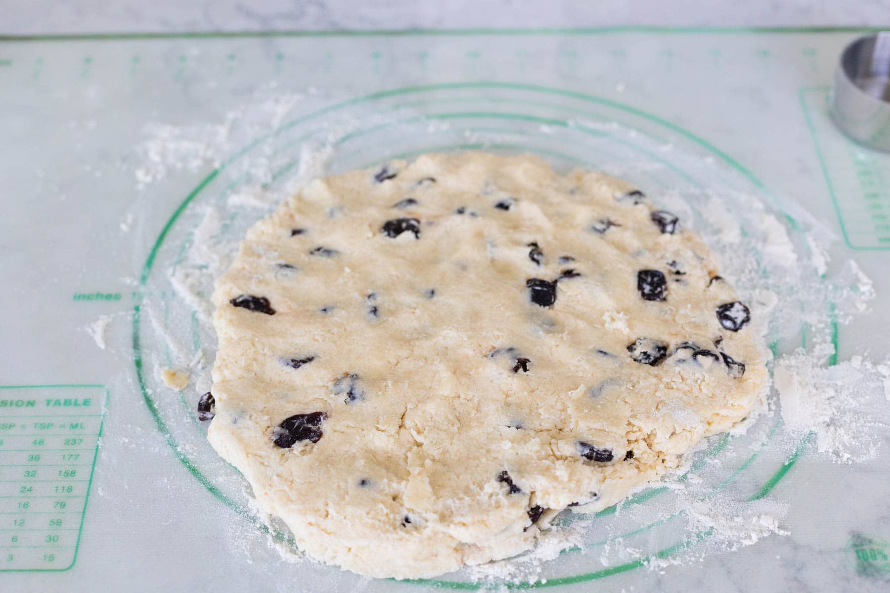 The dough for scones has been patted into a disc on a baking mat lined with flour.