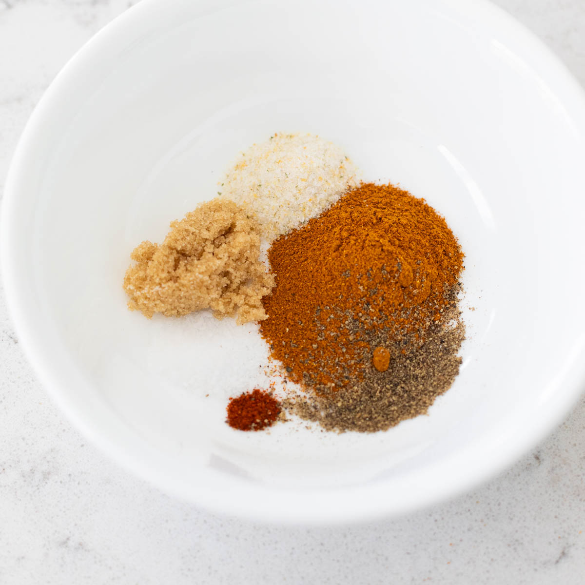 A white bowl is filled with the seasonings for the chicken wing rub.