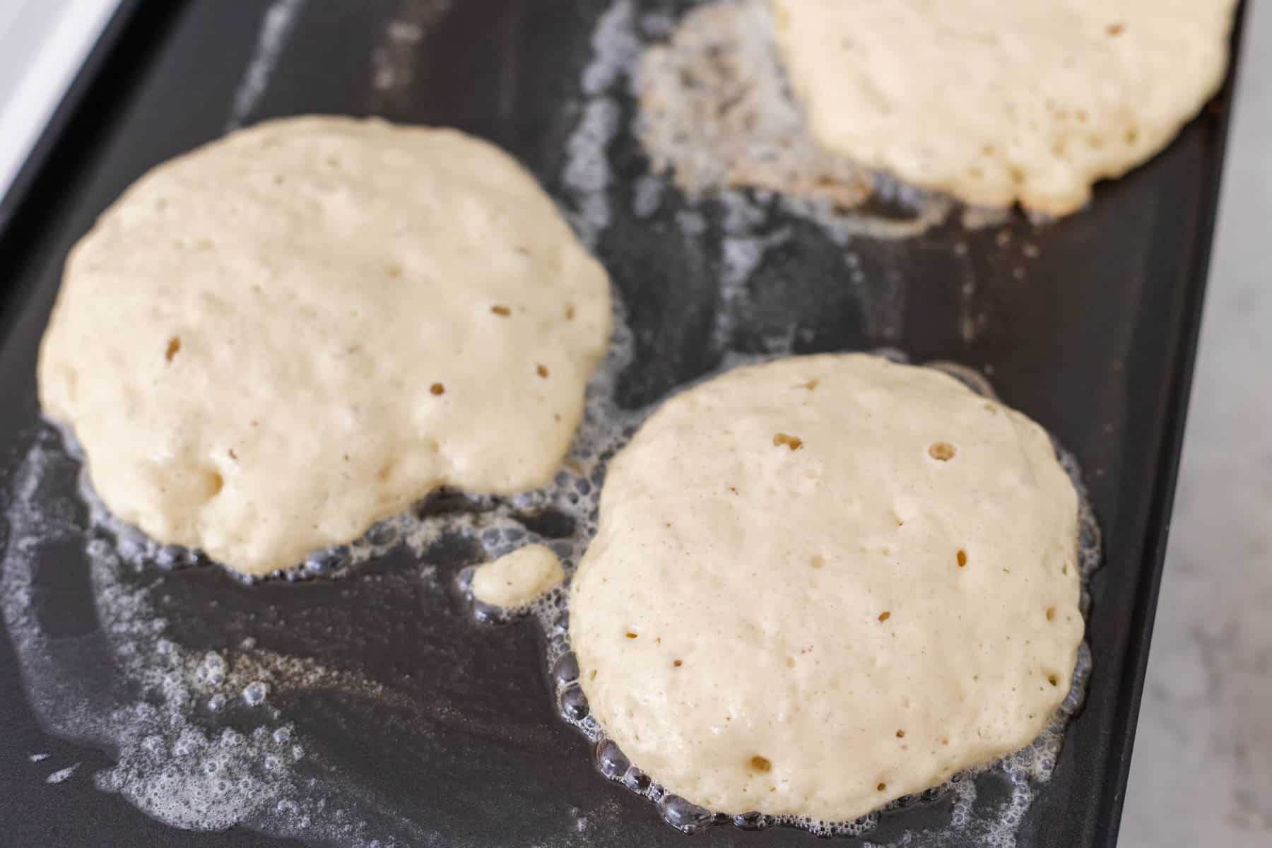 The pancakes have little air bubbles coming up through the batter.