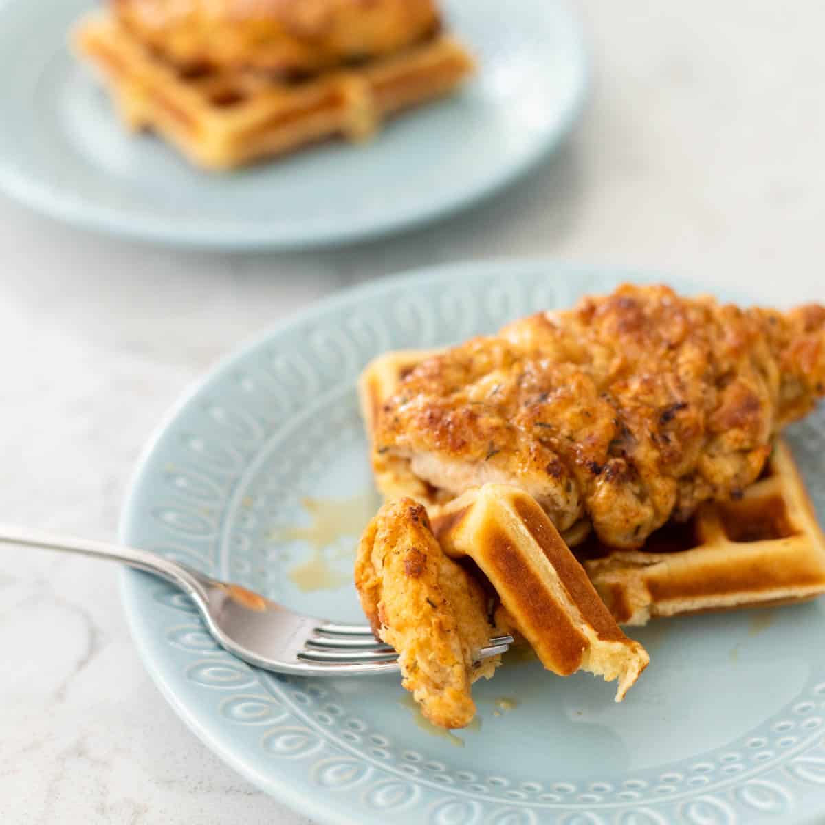 A bite has been cut from the chicken and waffles and is on the fork.