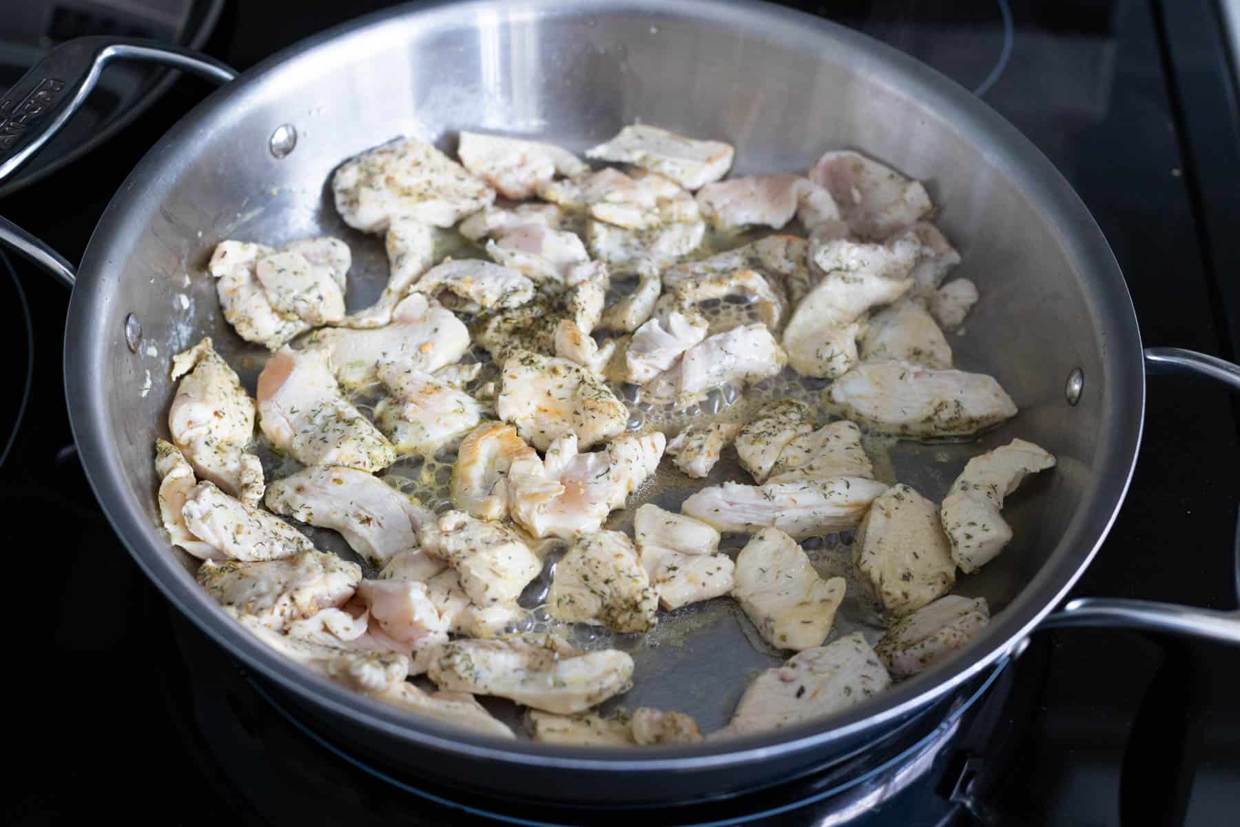 The chicken has cooked in the skillet and will now be transferred to a clean plate while the pasta cooks.