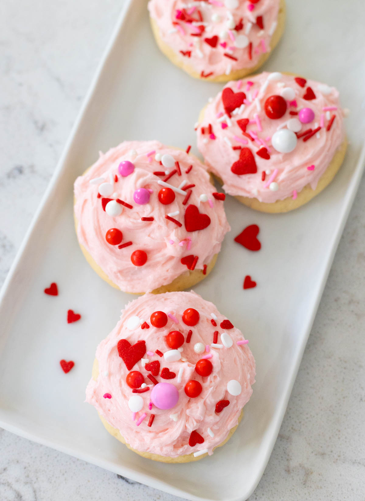 A white platter of pink, red, and white Valentine's Day sugar cookies.