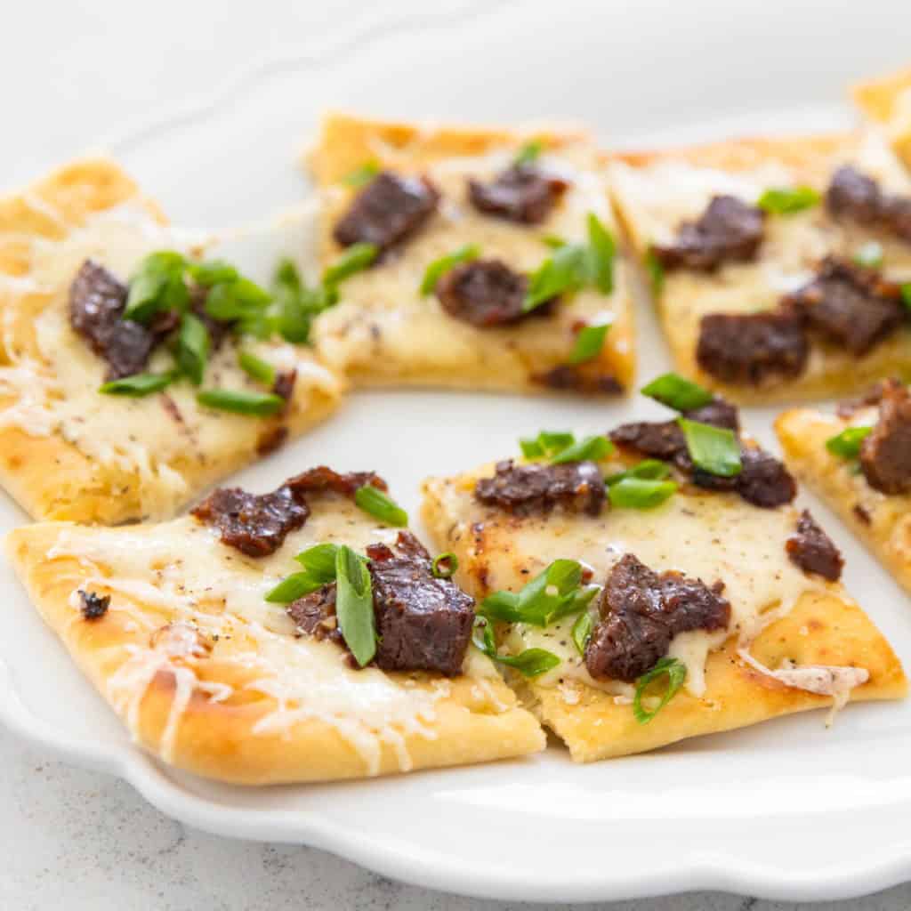 A white platter has squares of Mongolian beef flatbread.