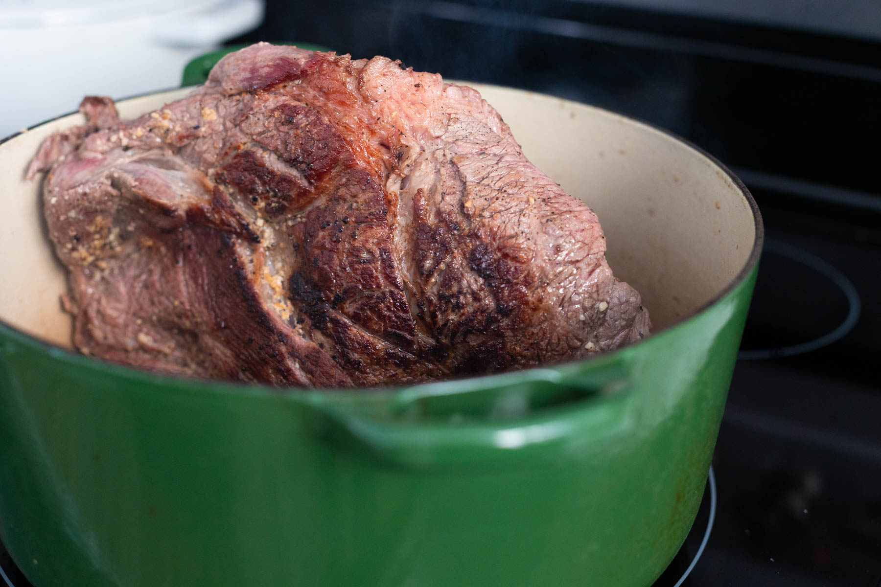 The large roast is in a large dutch oven getting seared on all sides.