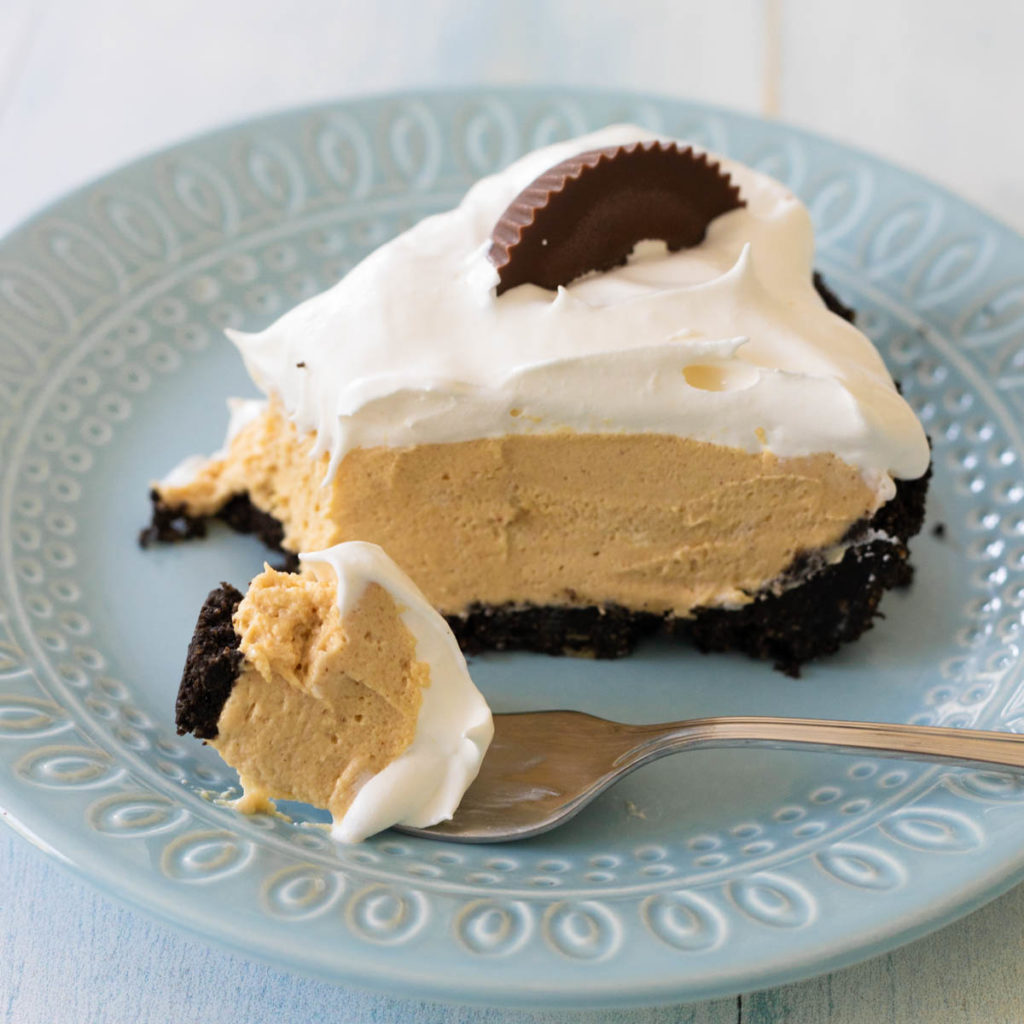 A slice of peanut butter pie on a blue plate. You can see the Oreo cookie crust and creamy filling.
