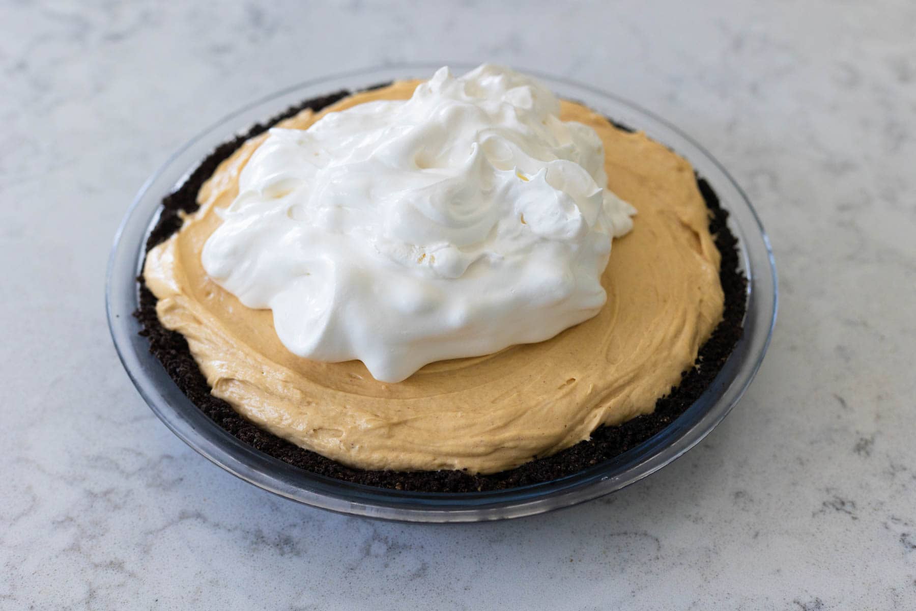 The whipped topping has been spooned over the peanut butter filling to frost the pie.