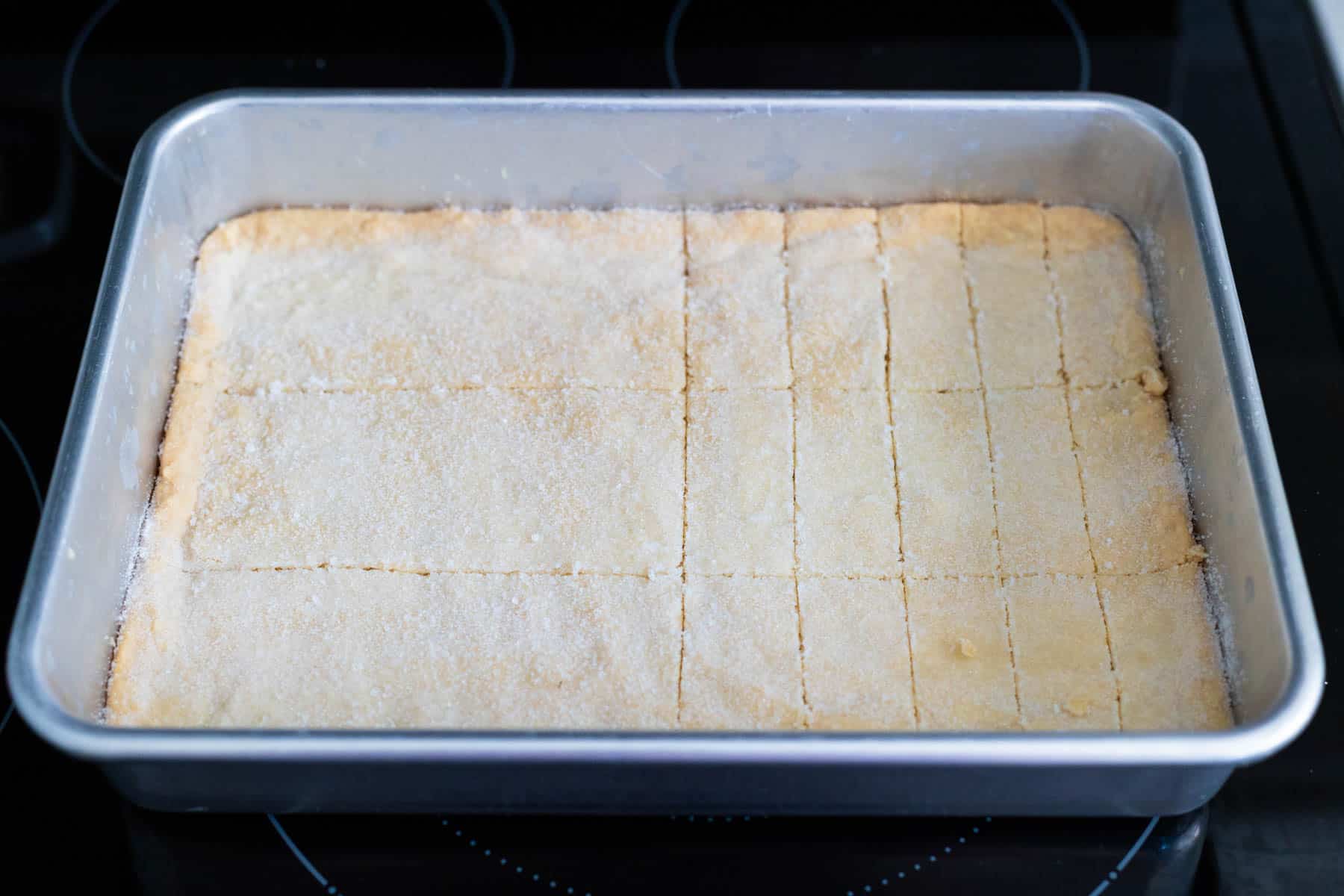 The shortbread cookies have been sliced on half the pan neat and evenly.