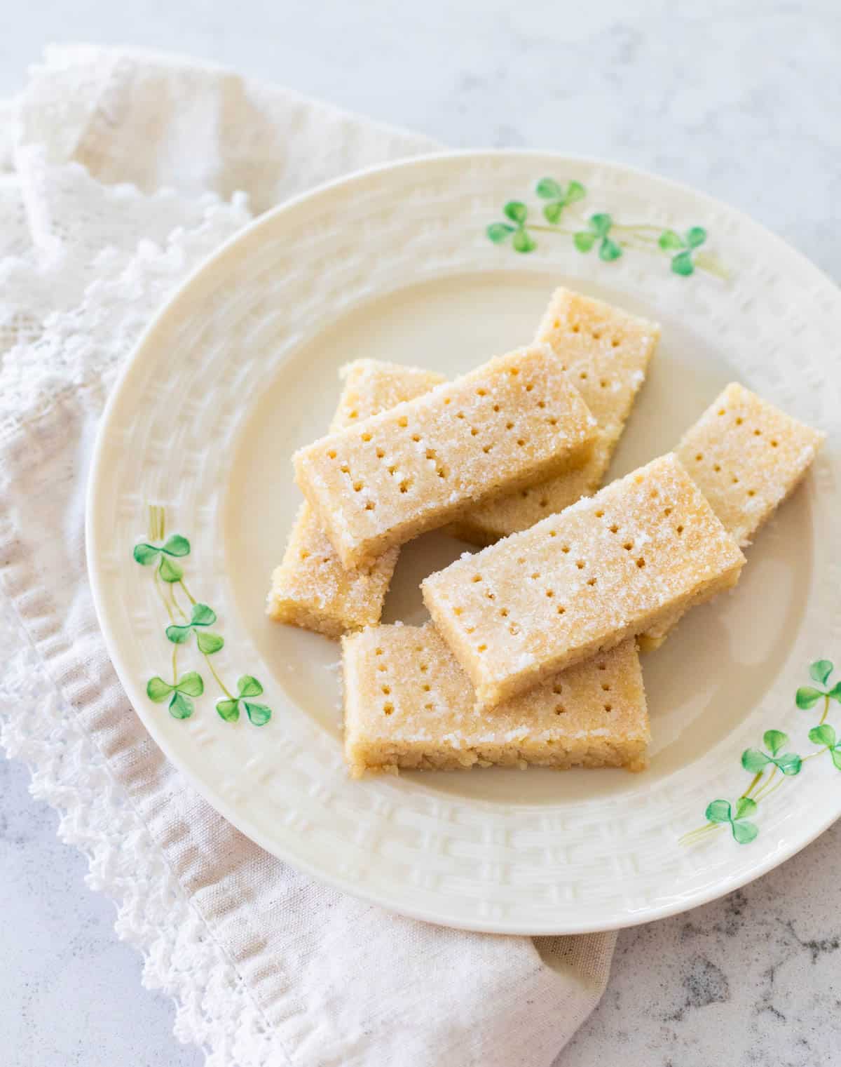 A shamrock plate has several rectangular Irish Shortbread cookies.