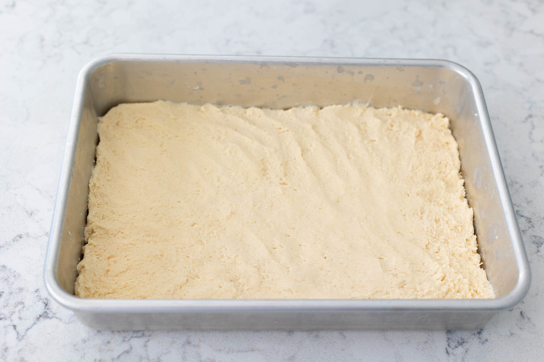 The shortbread cookie dough has been patted into place in a 9x13-inch baking pan.