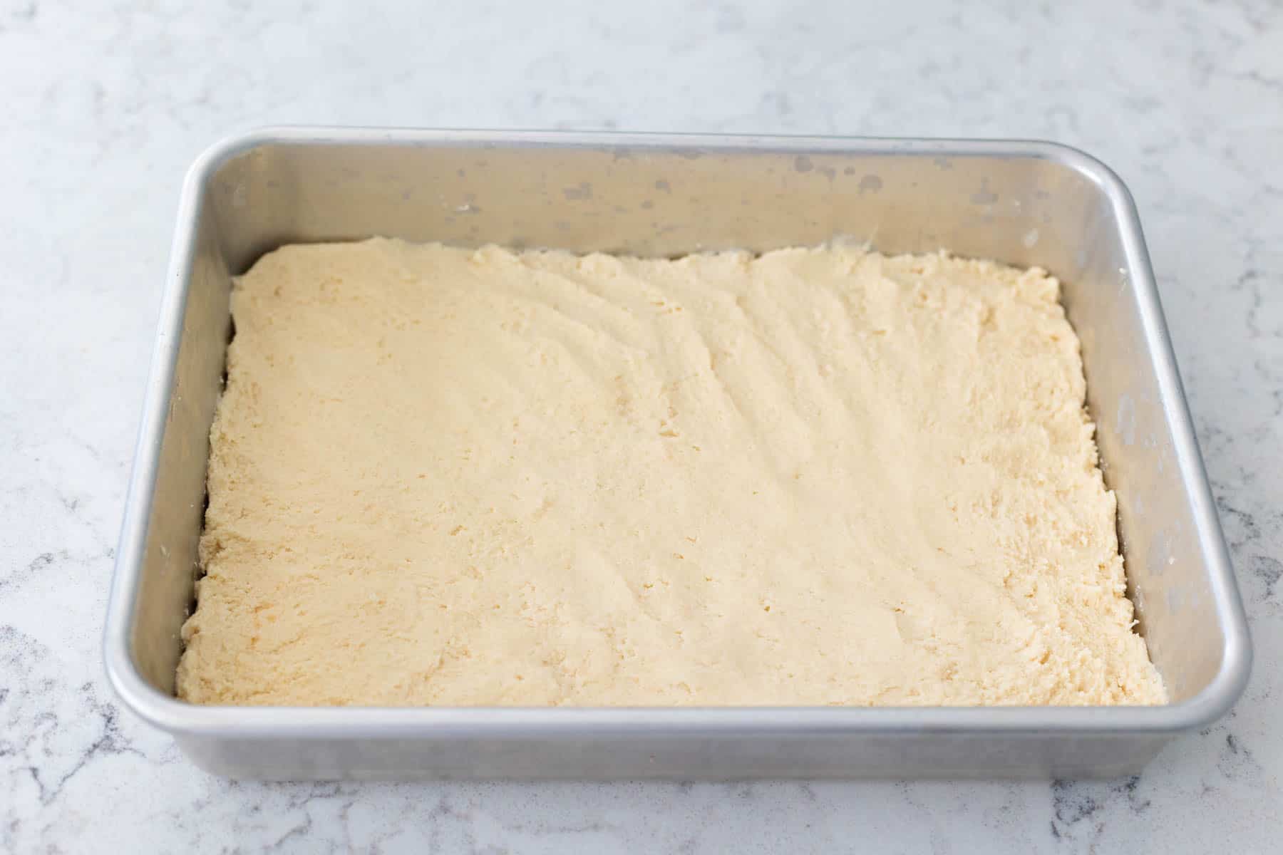 The shortbread cookie dough has been patted into place in a 9x13-inch baking pan.