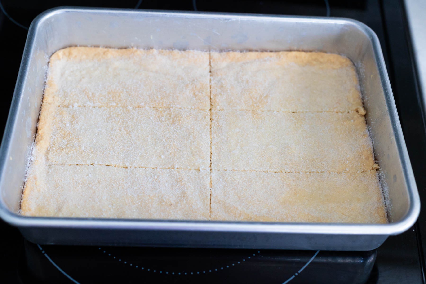The pan of shortbread cookies has a perpendicular cut half way down the pan.