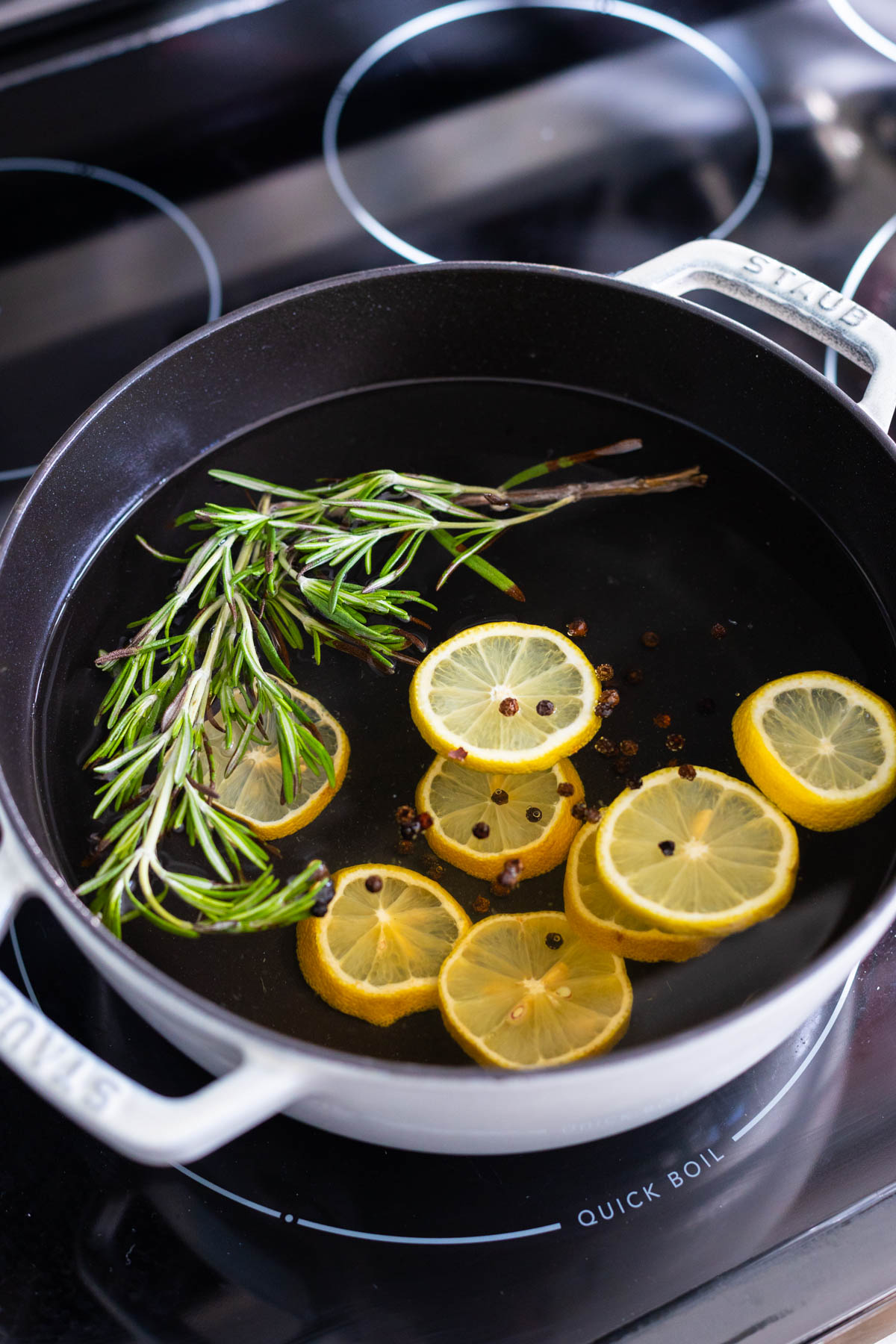 The simmer pot on the stove has lemon slices and fresh rosemary.