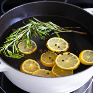 A simmer pot filled with lemons and rosemary is on the stovetop.
