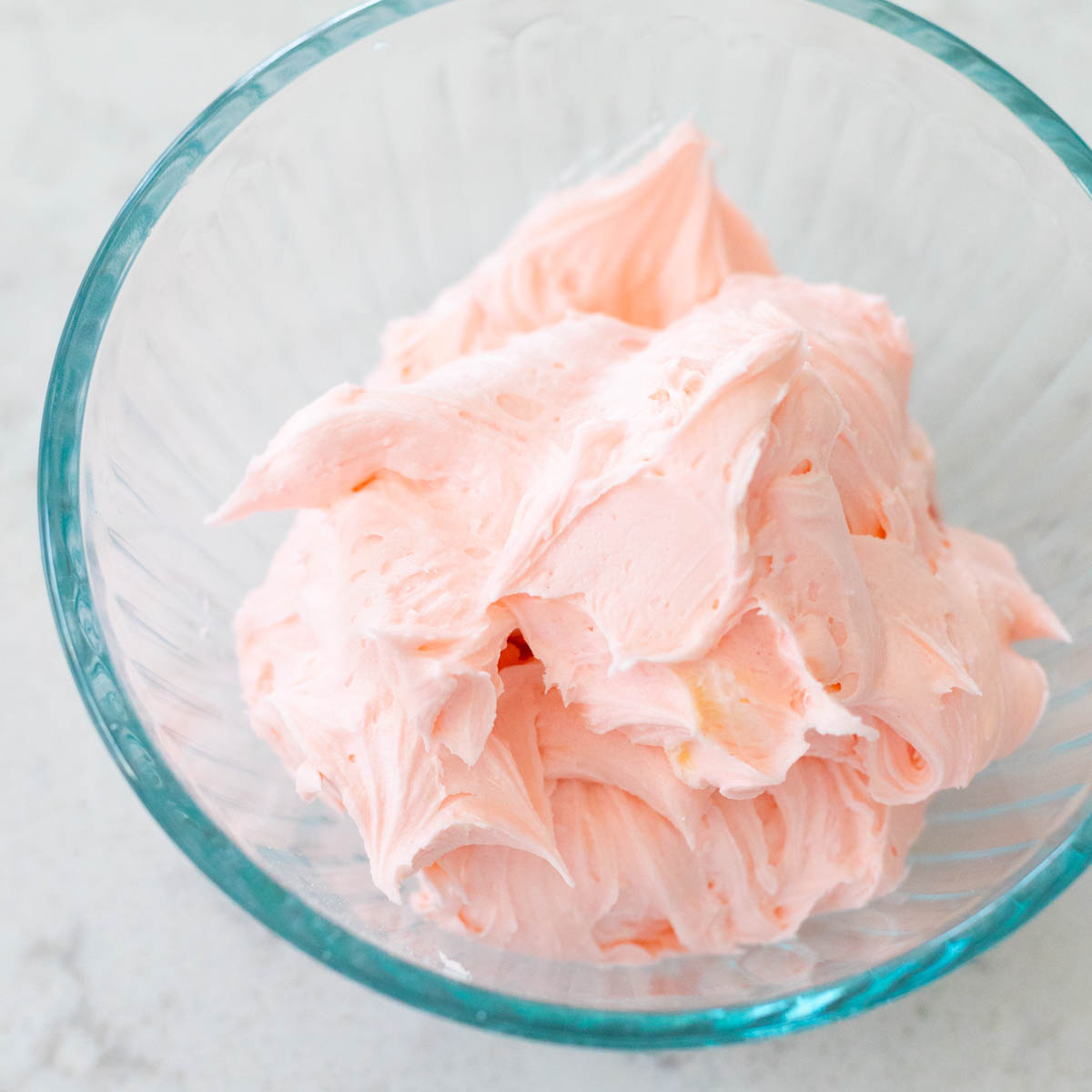 A bowl of sugar cookie frosting has been tinted pink.