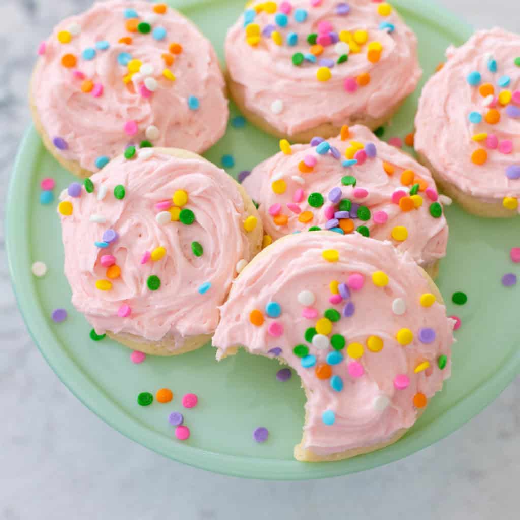 A plate of pink sugar cookies with sprinkles.