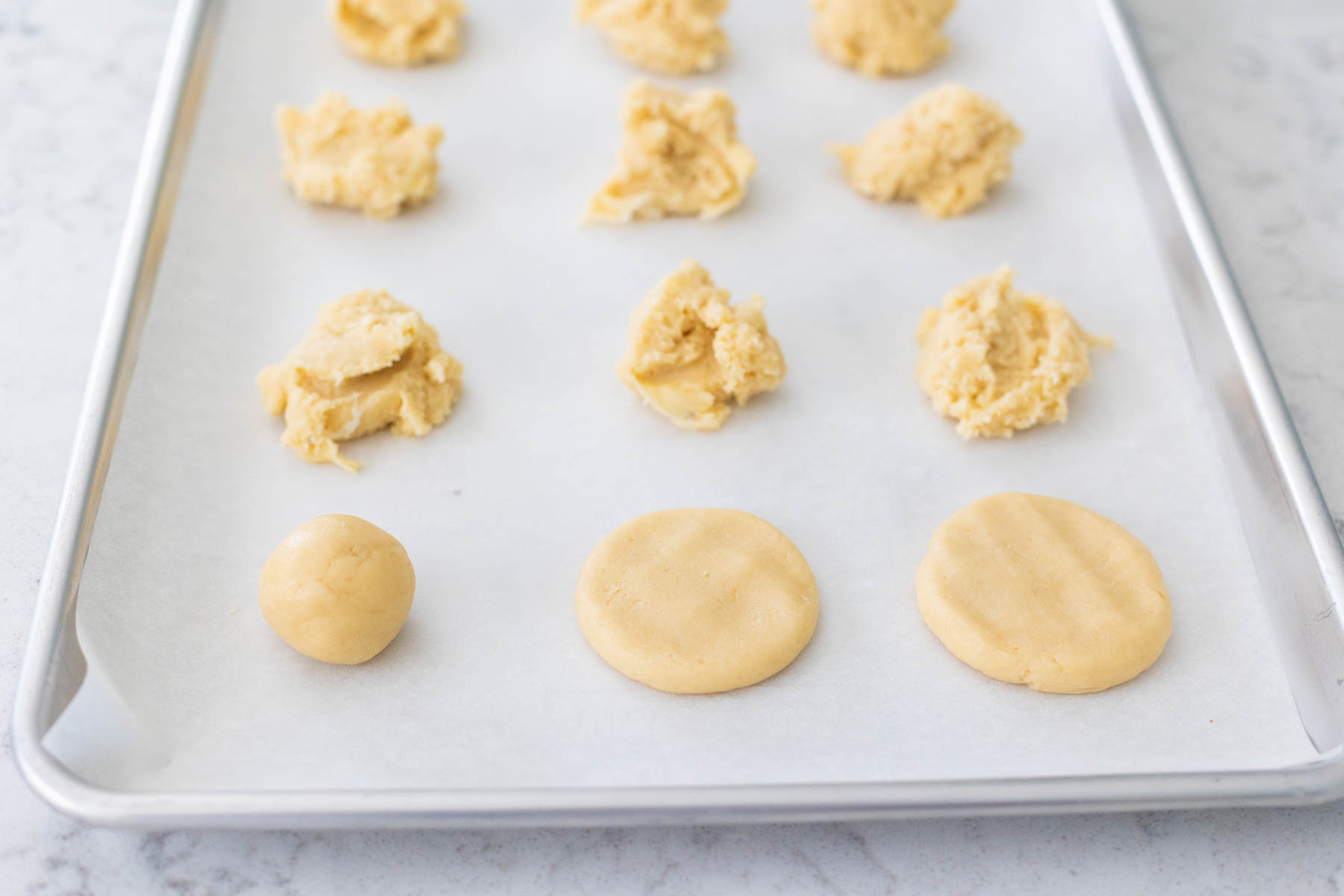 The baking sheet with cookies shows how to roll the dough into smooth balls and then flatten them into a pancake-like shape before baking.