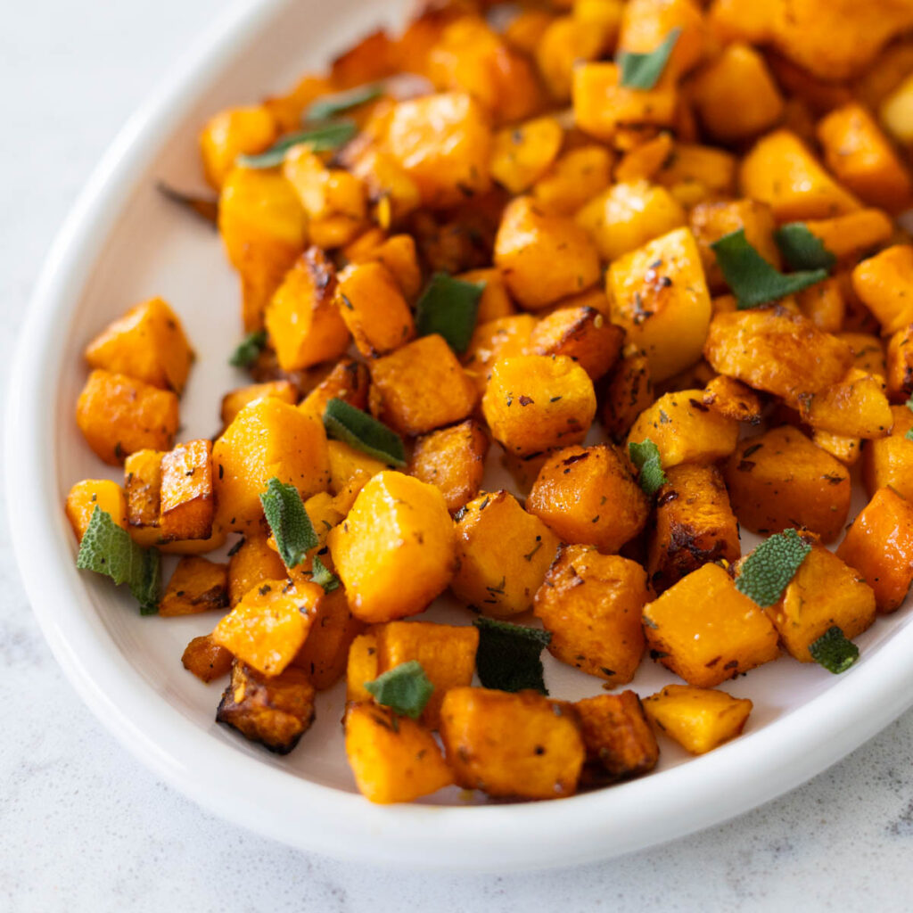 A white platter of cubed butternut squash has been air fried to a golden crispy brown.