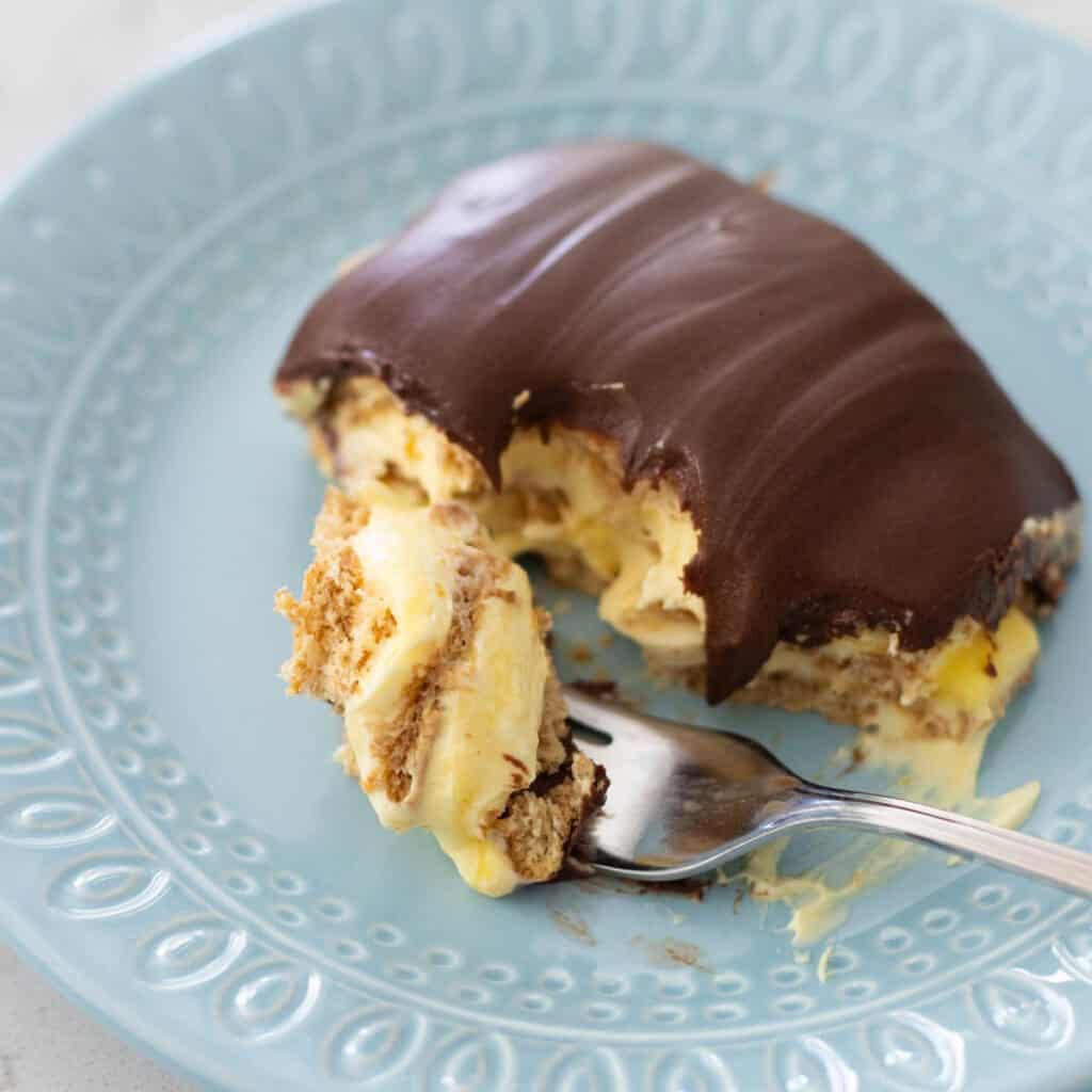 A serving of chocolate topped no bake vanilla pudding torte with graham crackers on a blue plate.