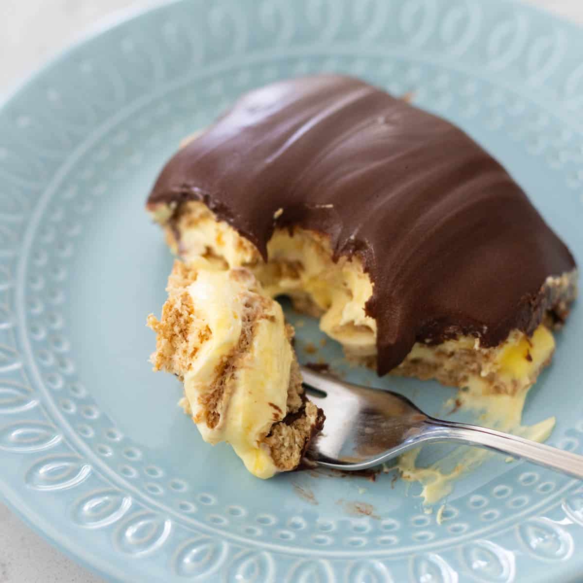 A serving of chocolate topped no bake vanilla pudding torte with graham crackers on a blue plate.