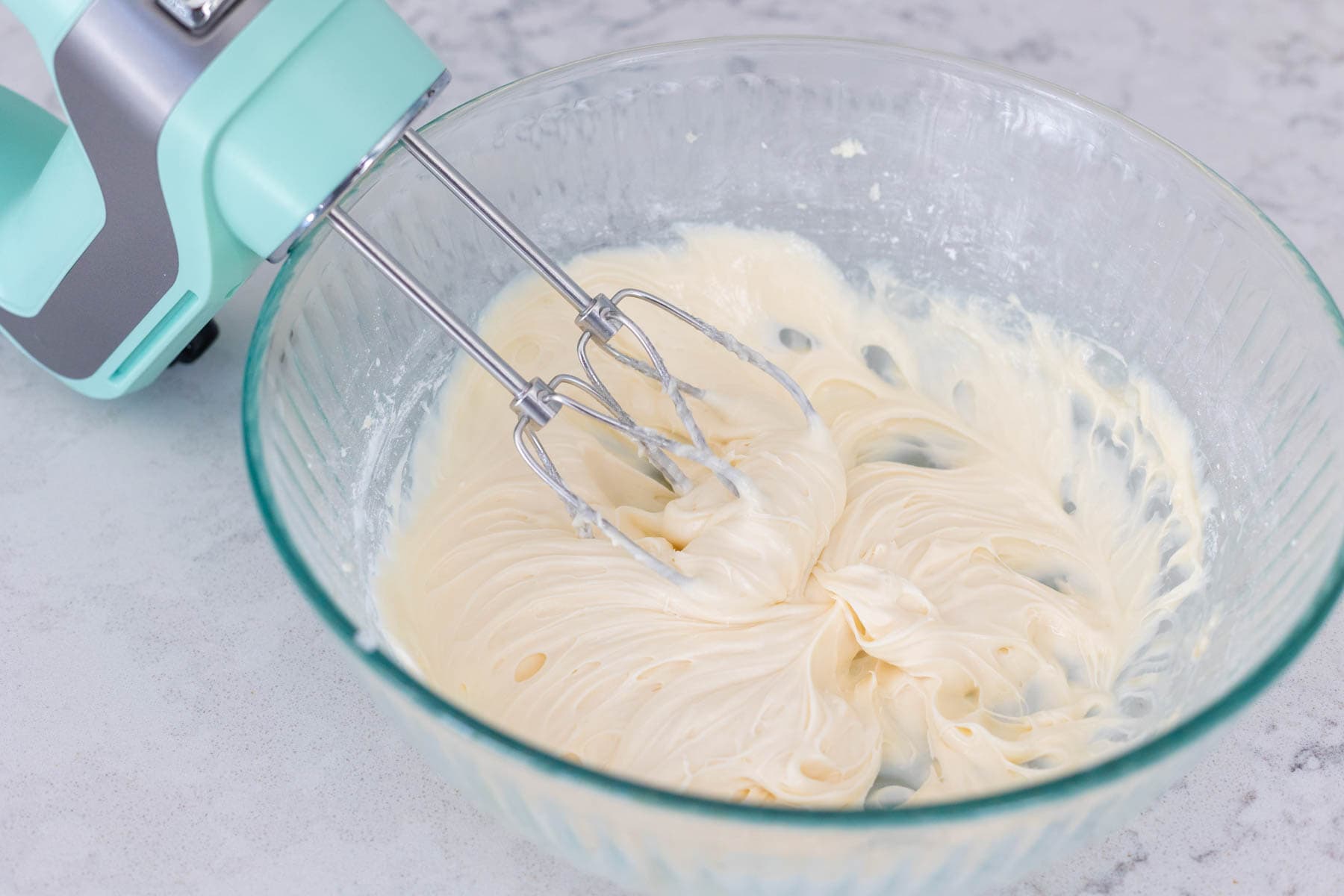 The finished cream cheese icing is in the mixing bowl.