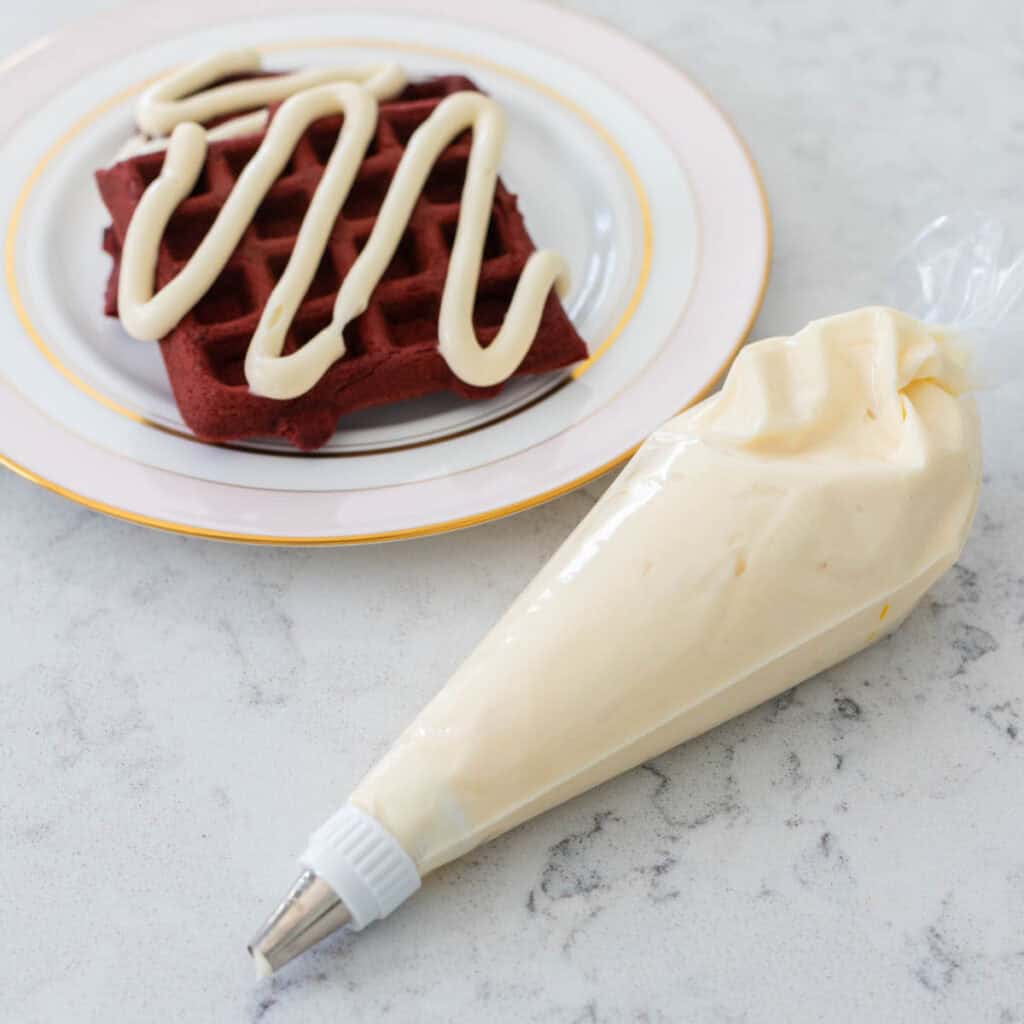 A piping bag filled with cream cheese icing for piping onto waffles and cakes.