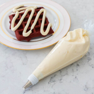 A piping bag filled with cream cheese icing for piping onto waffles and cakes.