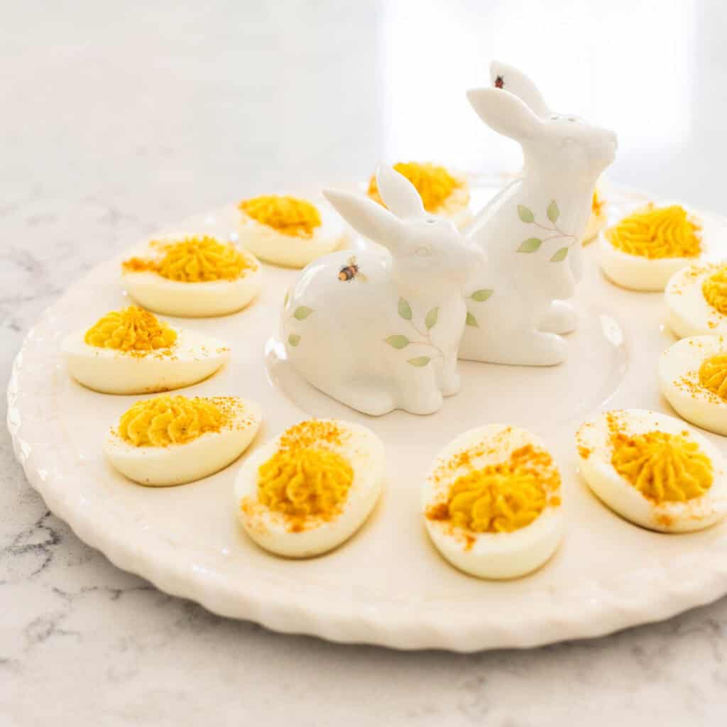 A platter of deviled eggs has 2 bunny shaped salt and pepper shakers in the center.