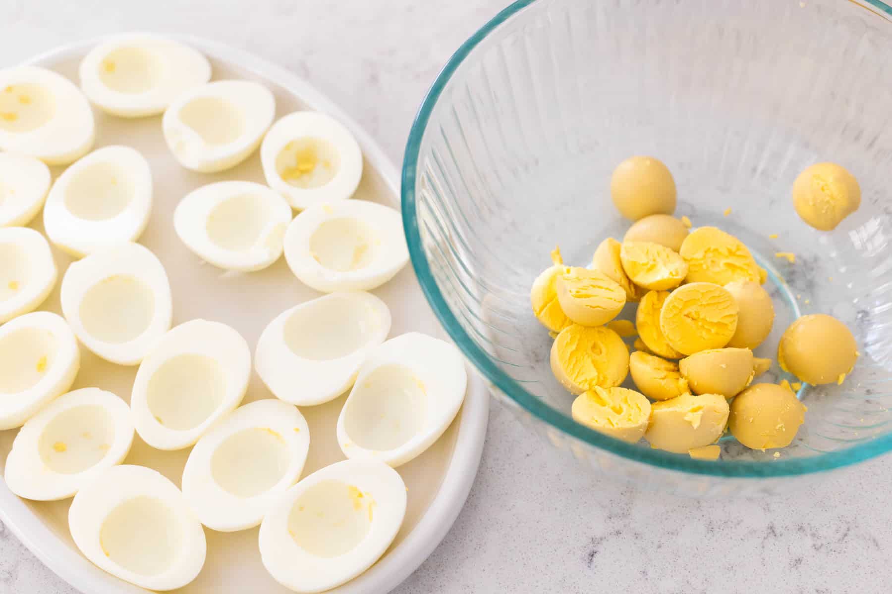 The eggs have been sliced in half and the yolks popped out into a mixing bowl.