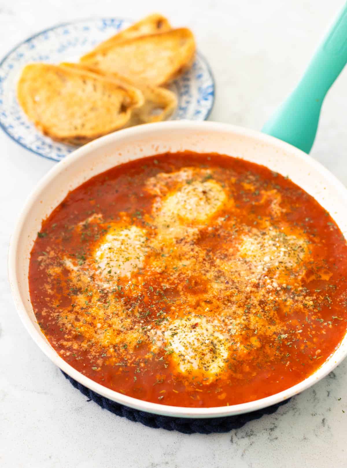 The cooked eggs are in the skillet next to a plate of toast.