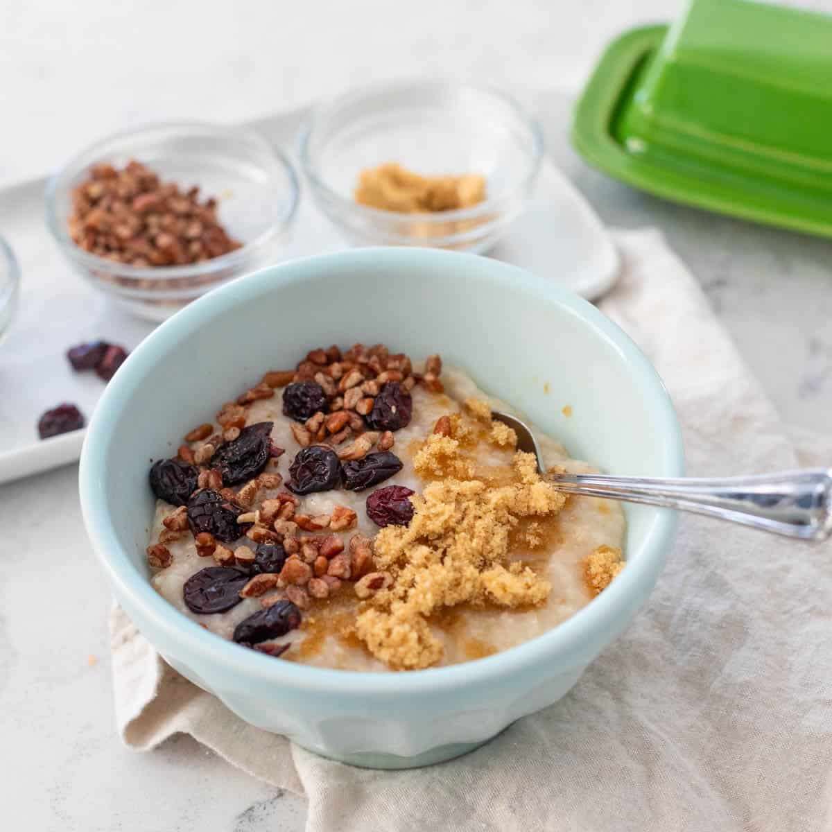 A bowl of Irish oatmeal has dried craisins and chopped pecans on top.