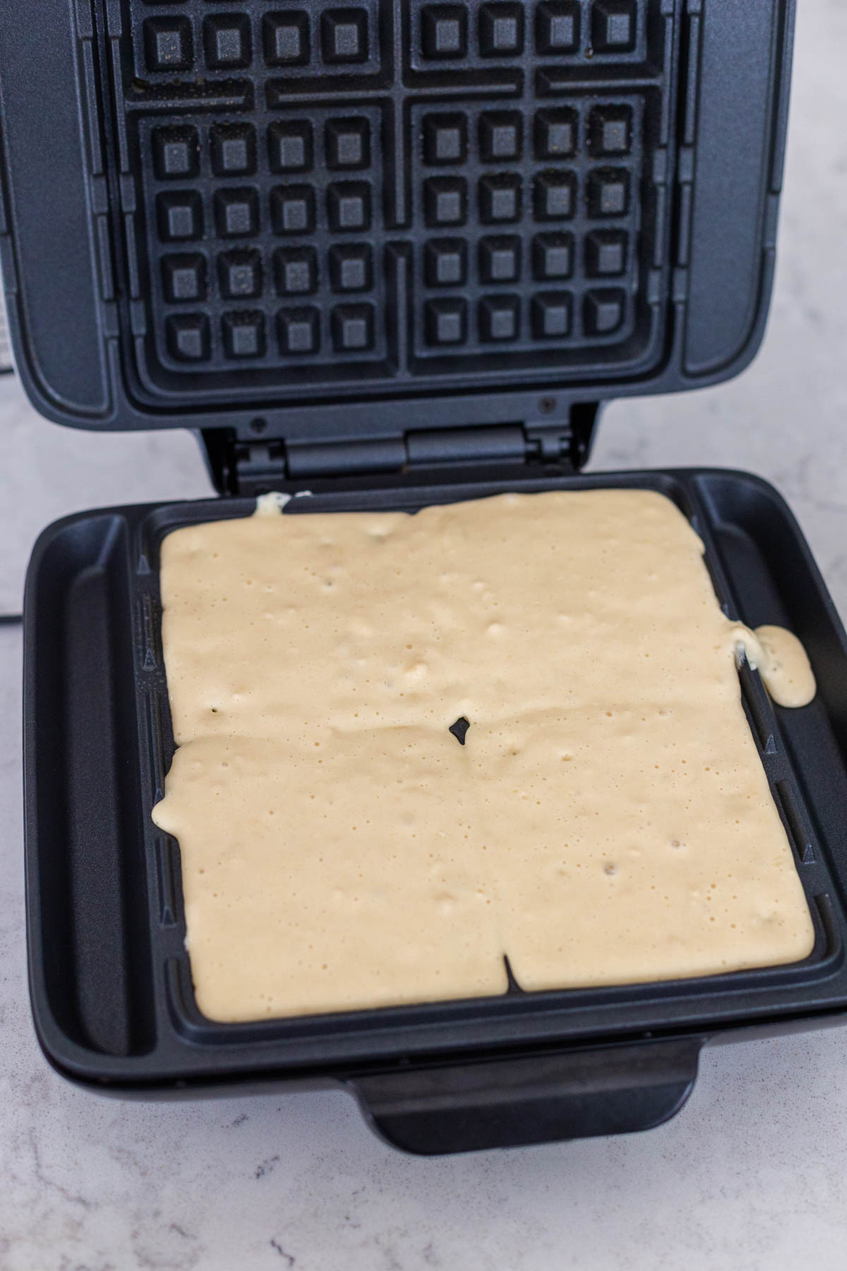 The waffles are added to the waffle maker.
