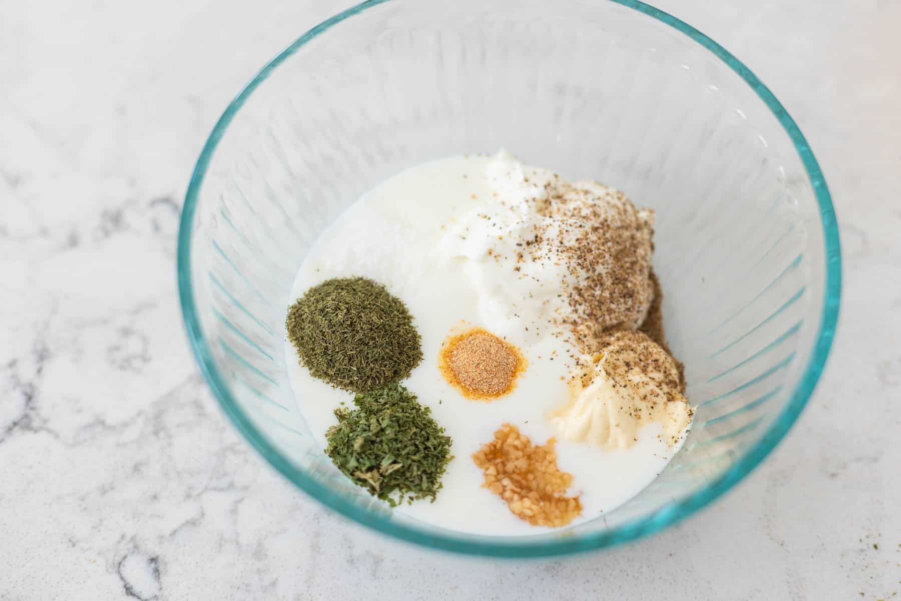 The ingredients for the ranch dip are in a mixing bowl ready to be stirred together.