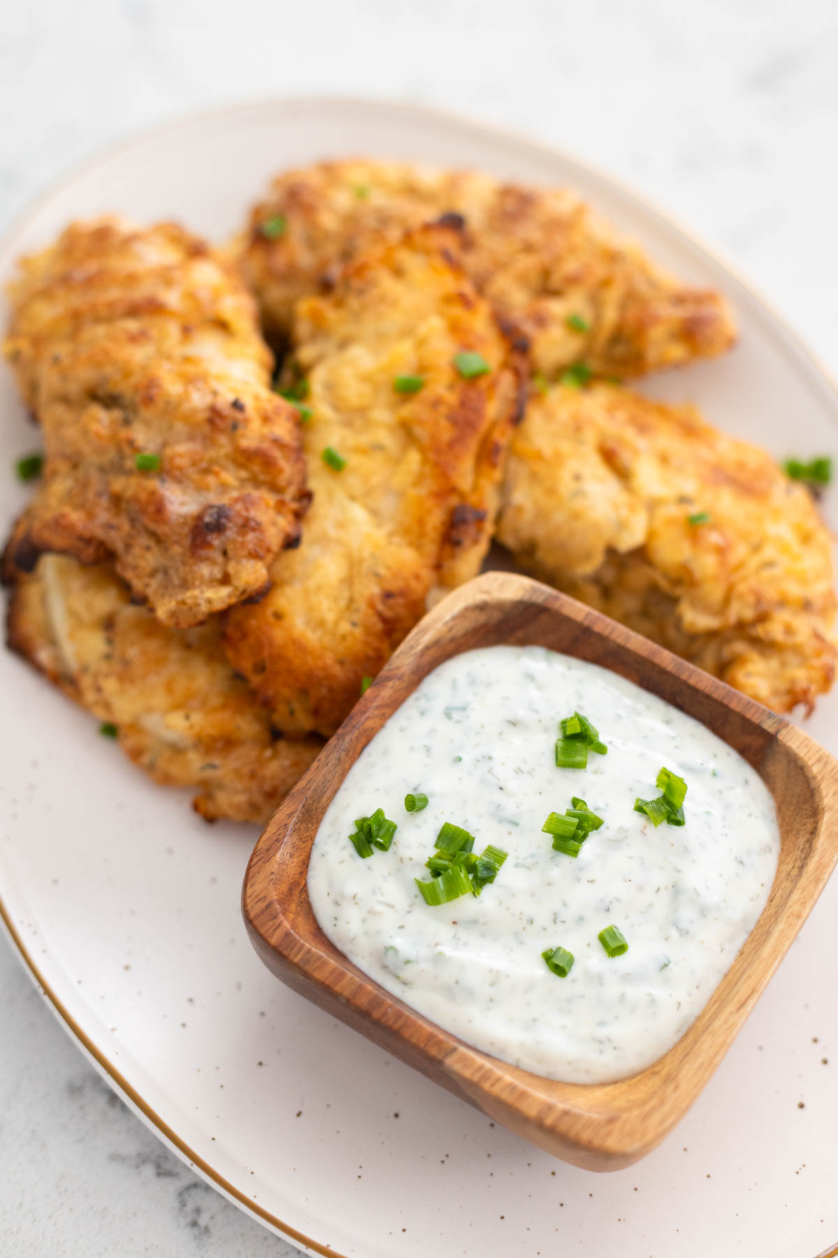 Chicken tenders are served on a platter with a cup of ranch dip.