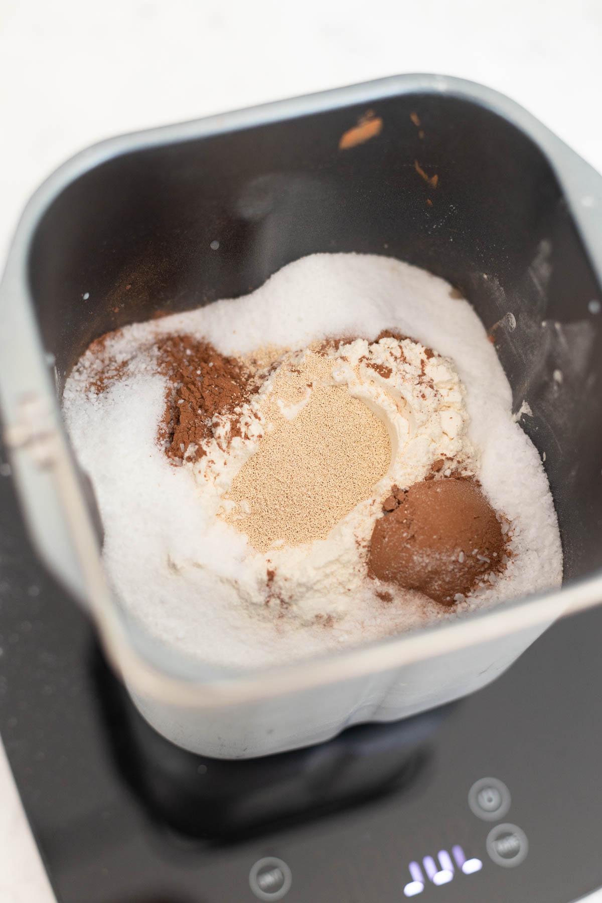 The flour, cocoa powder, and yeast are in the bread pan.