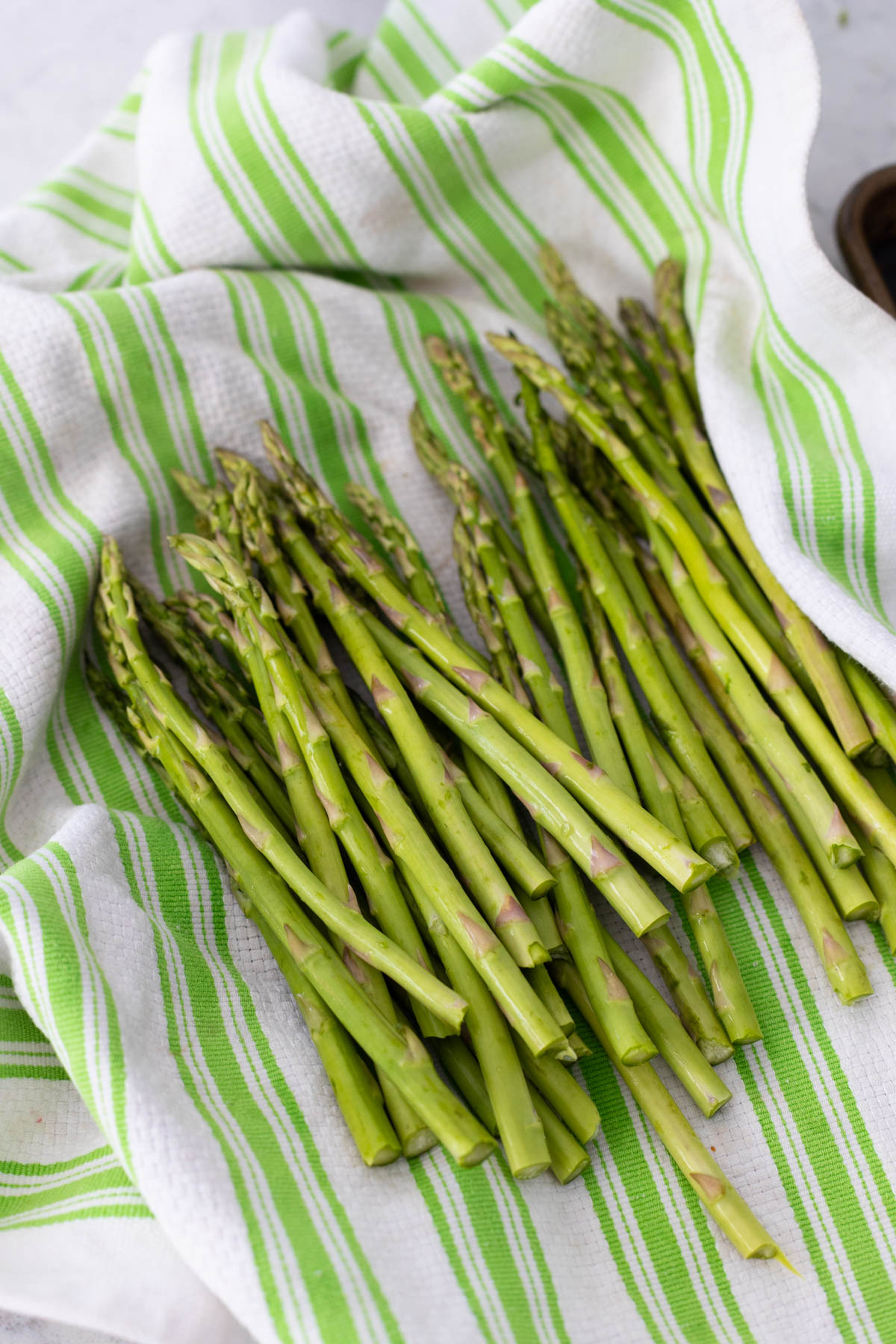 The washed asparagus is drying on a kitchen towel.