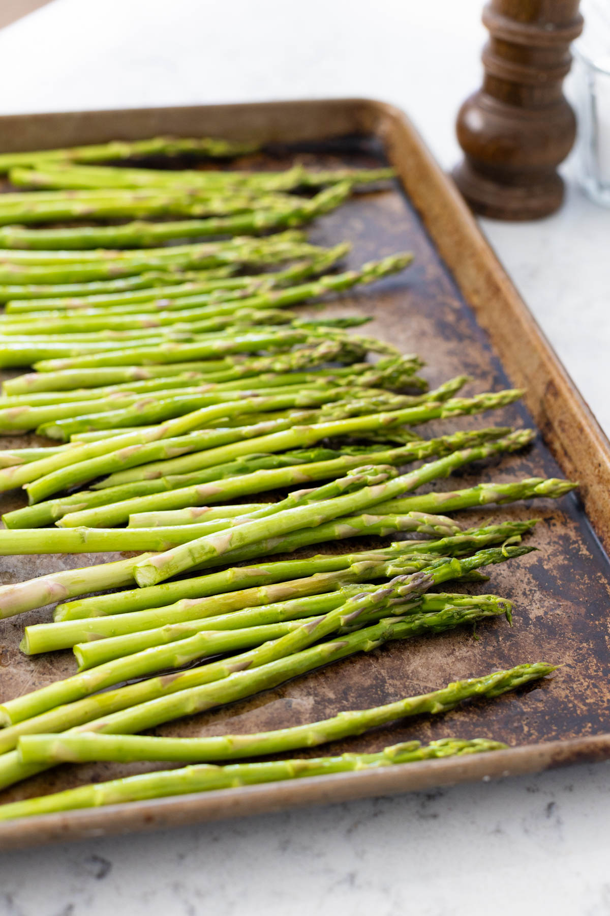 The olive oil, salt, and pepper have been added to the fresh asparagus spears.