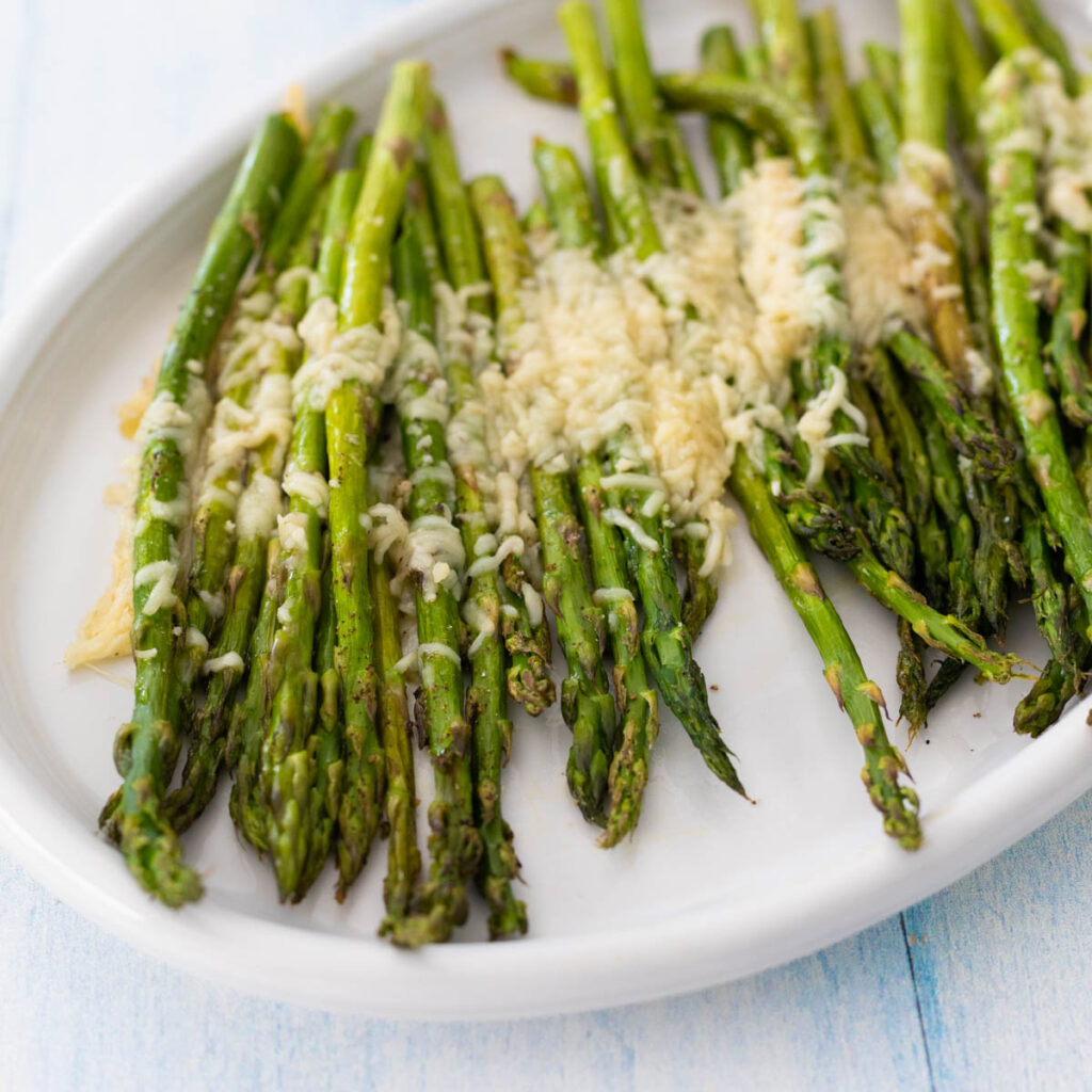 A white platter of parmesan roasted asparagus.