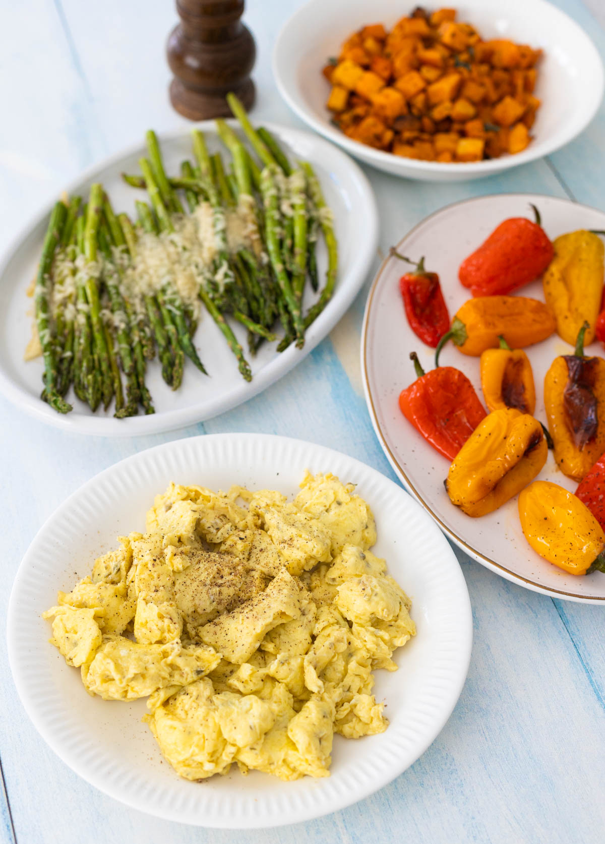 The plate of scrambled eggs sits in a buffet with plates of roasted vegetables all around.