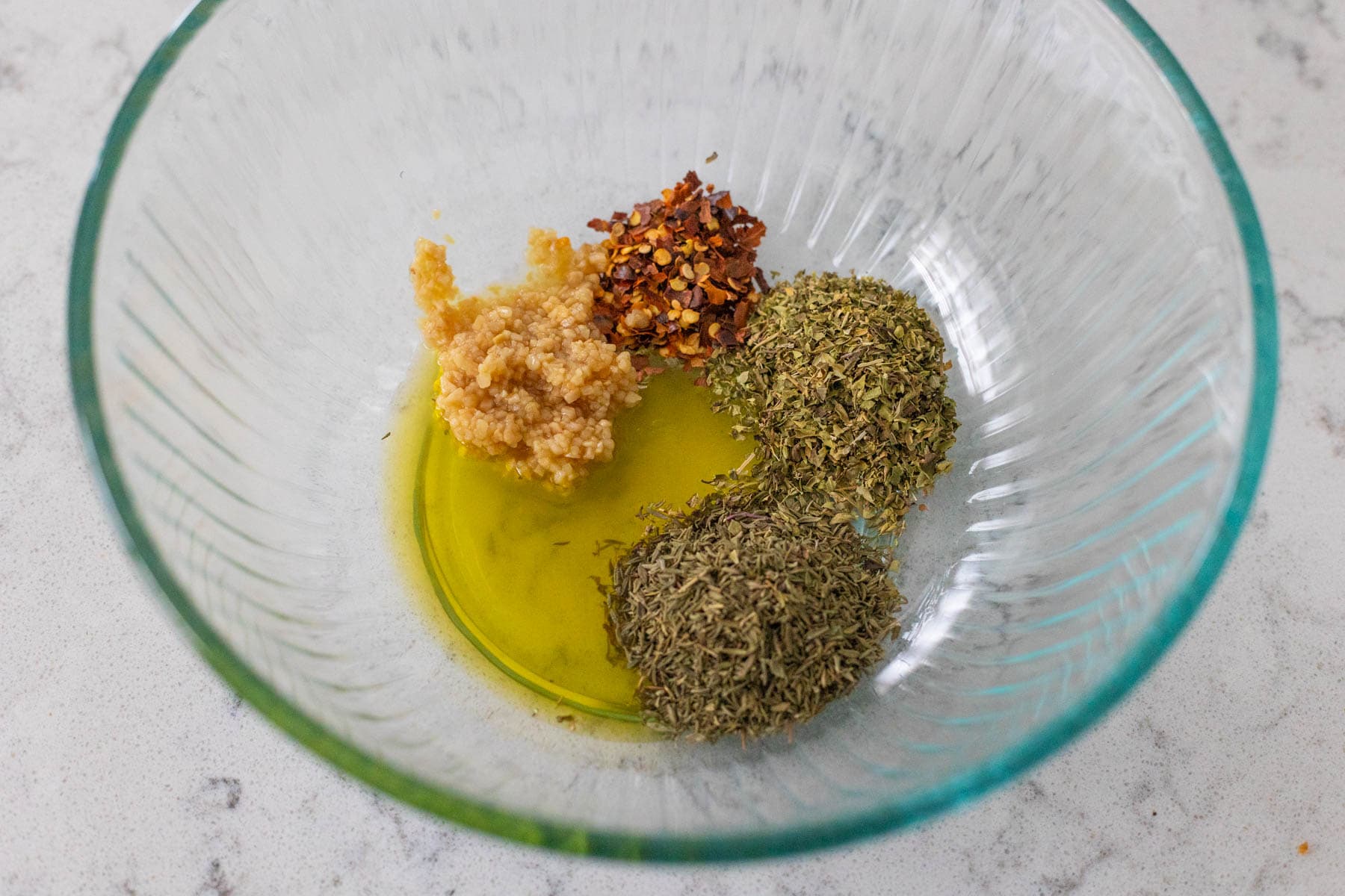 The spices are in a mixing bowl with olive oil.