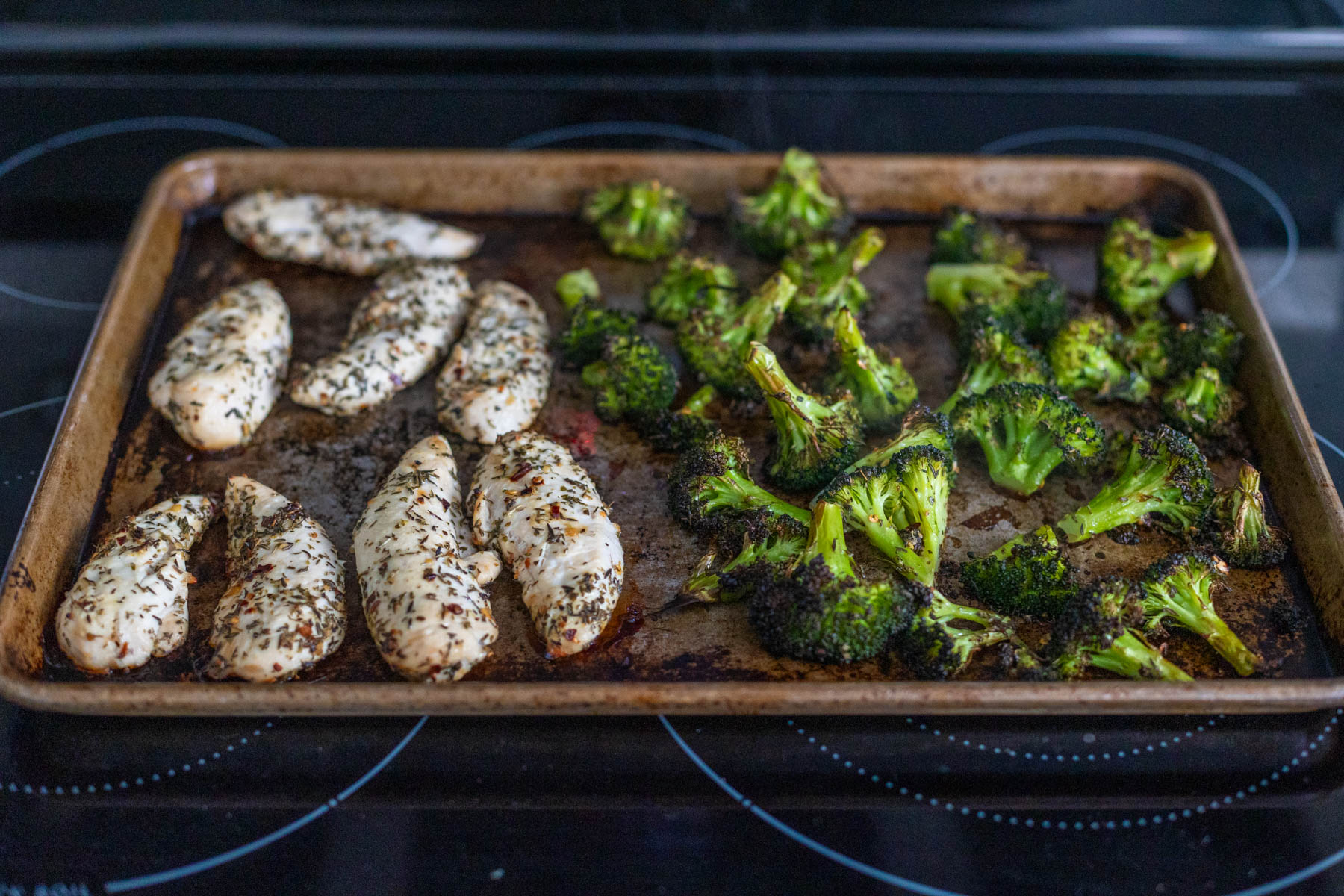 The sheet pan is fresh out of the oven, the chicken and broccoli are fully cooked.